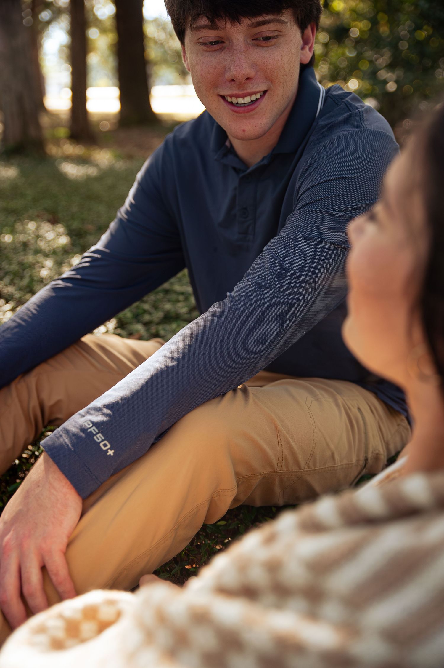 A couple sitting together outdoors on a sunny autumn day, sharing a relaxed moment in casual attire.