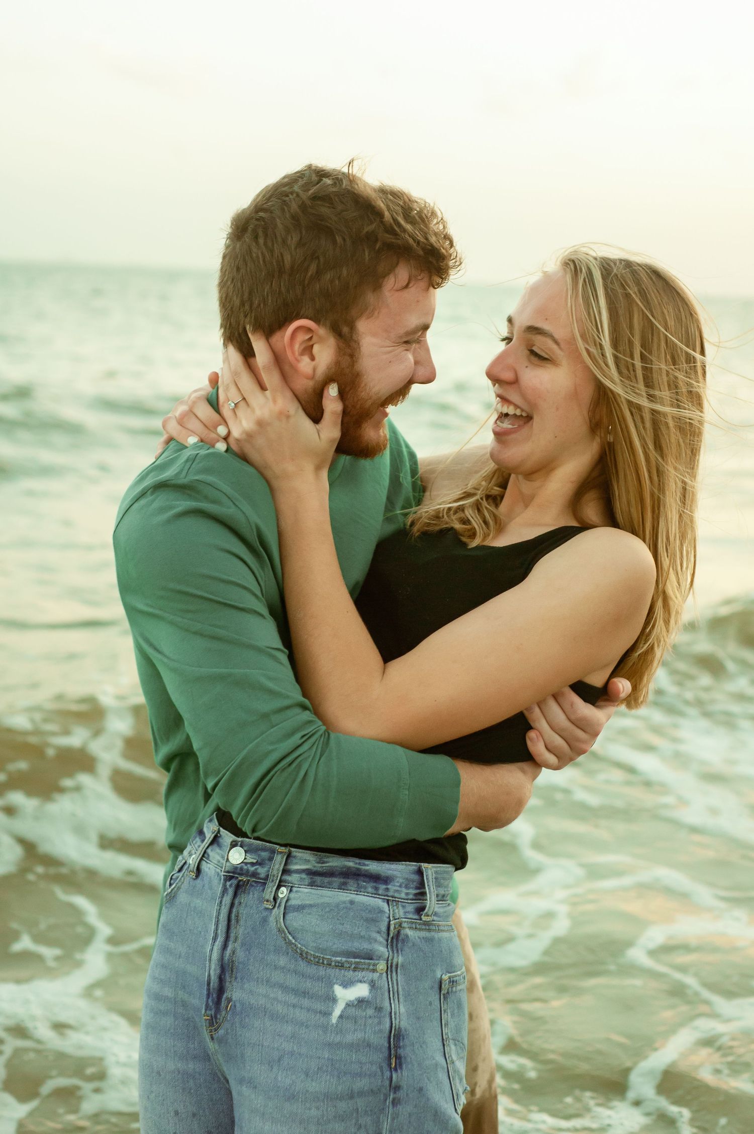 Romantic seaside embrace with waves breaking in the background during sunset.