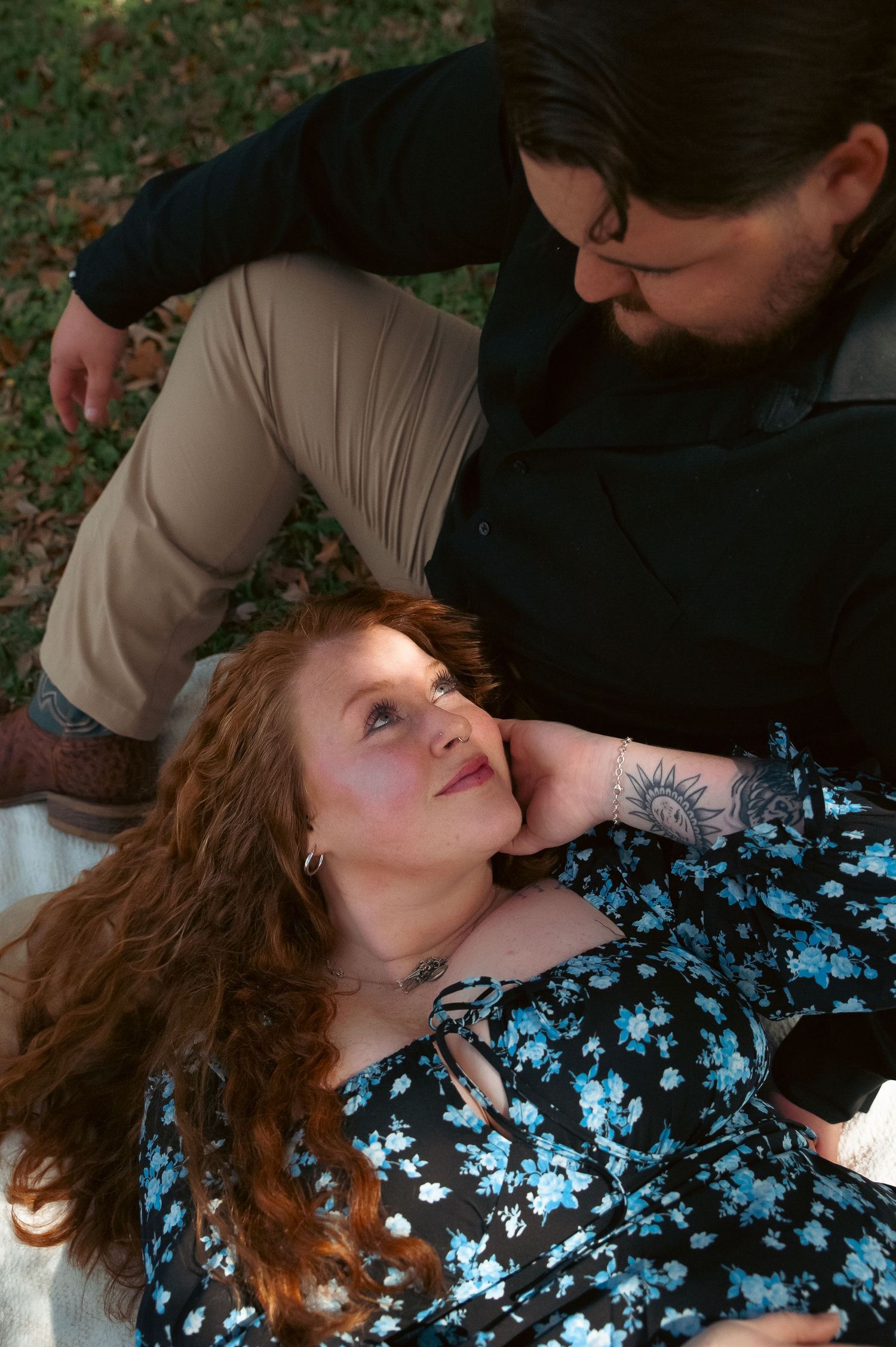 A tender moment captured during an outdoor picnic date under a tree.