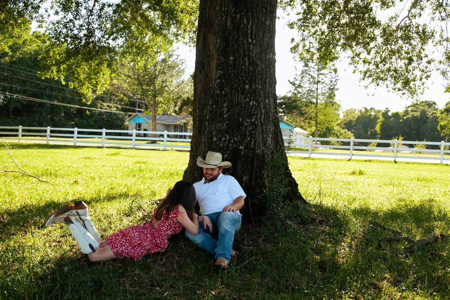 A scenic outdoor photoshoot under a large tree with a white blanket laid out on the grass.