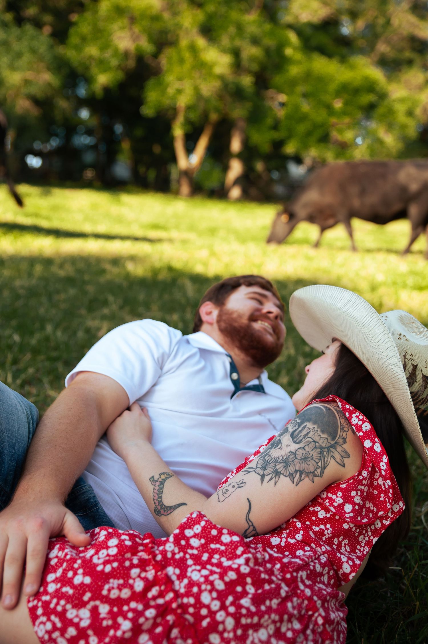 A couple lounging on grass showing visible tattoos and summer attire.