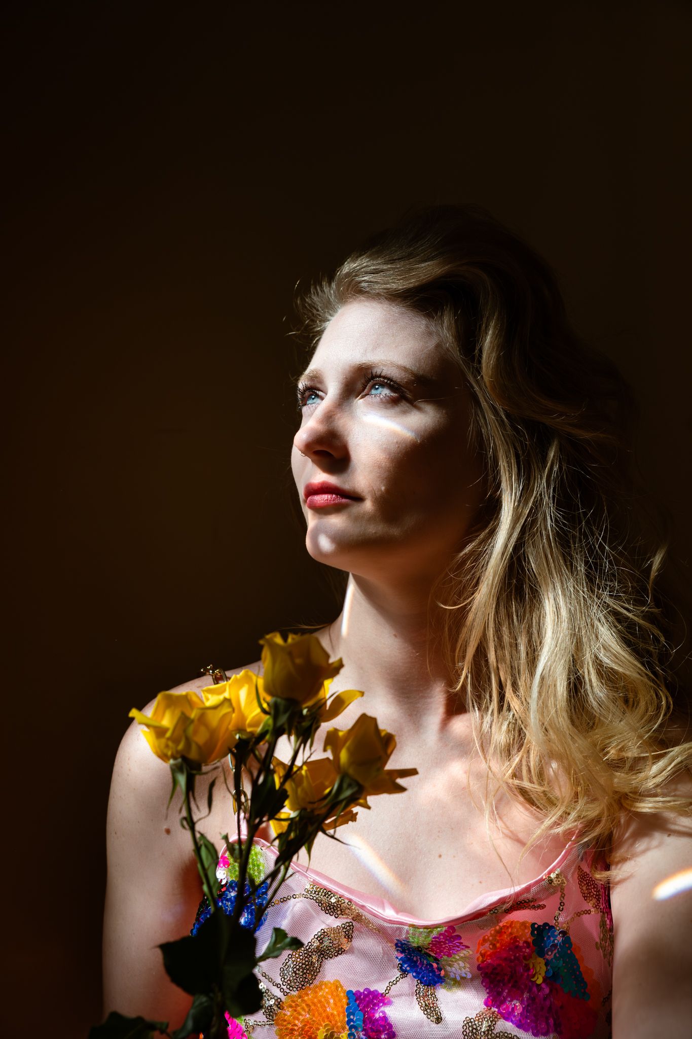 A creative portrait series showing a model wearing colorful floral decorations against a dark background.