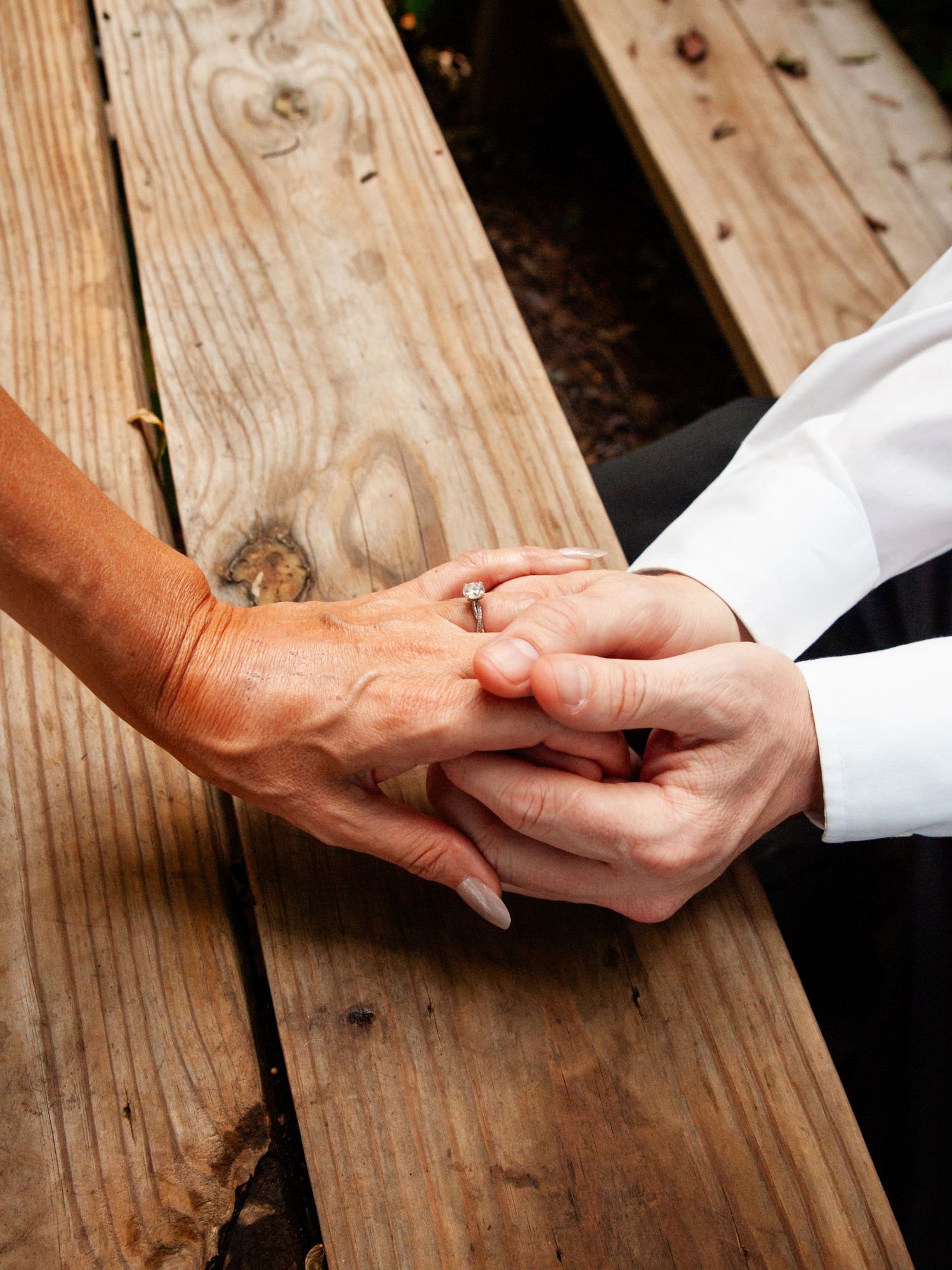 Three sequential photos showing two hands reaching out and clasping together on a rustic wooden surface.