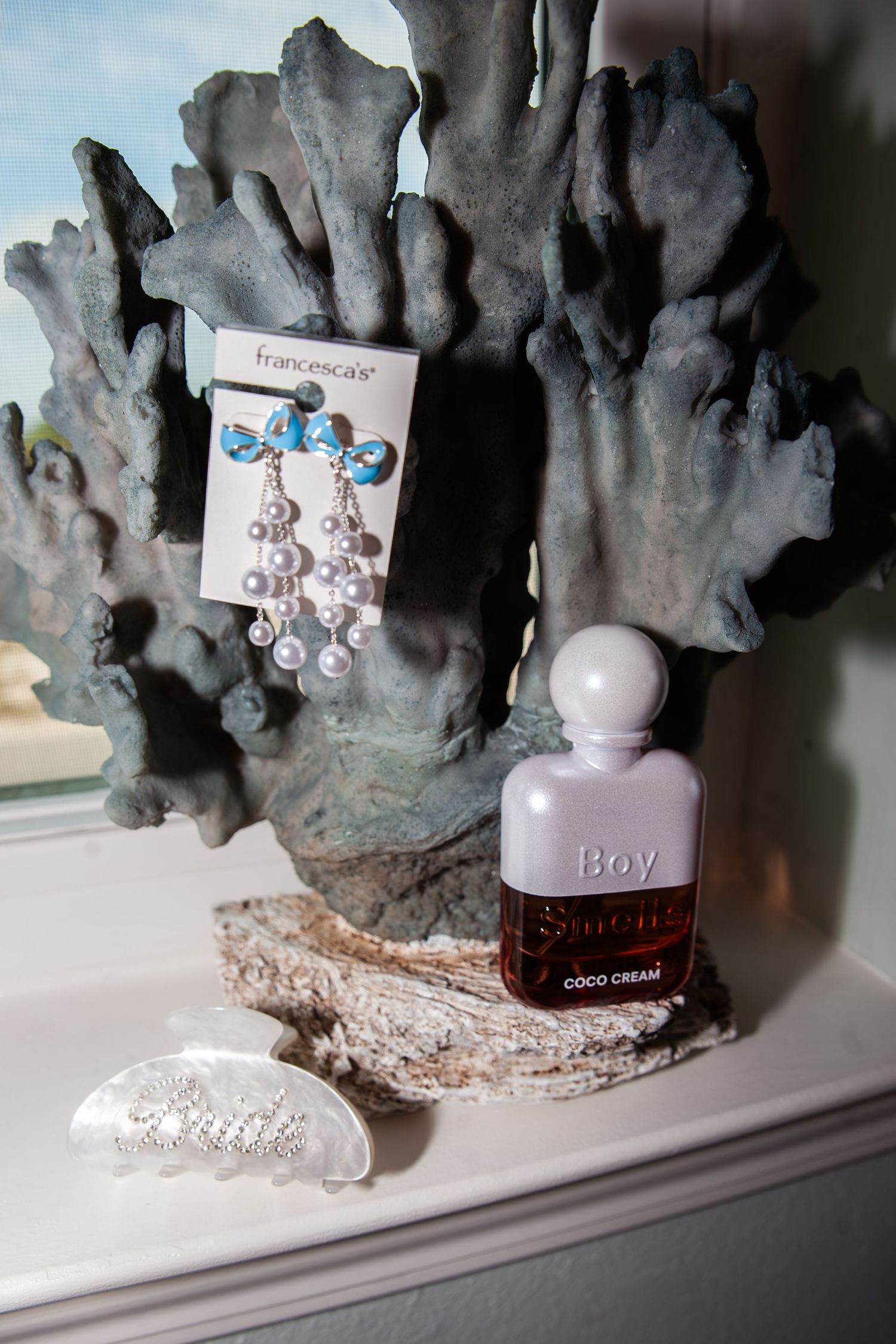 Small perfume bottles displayed on a white shelf against a dark textured backdrop create an elegant arrangement.