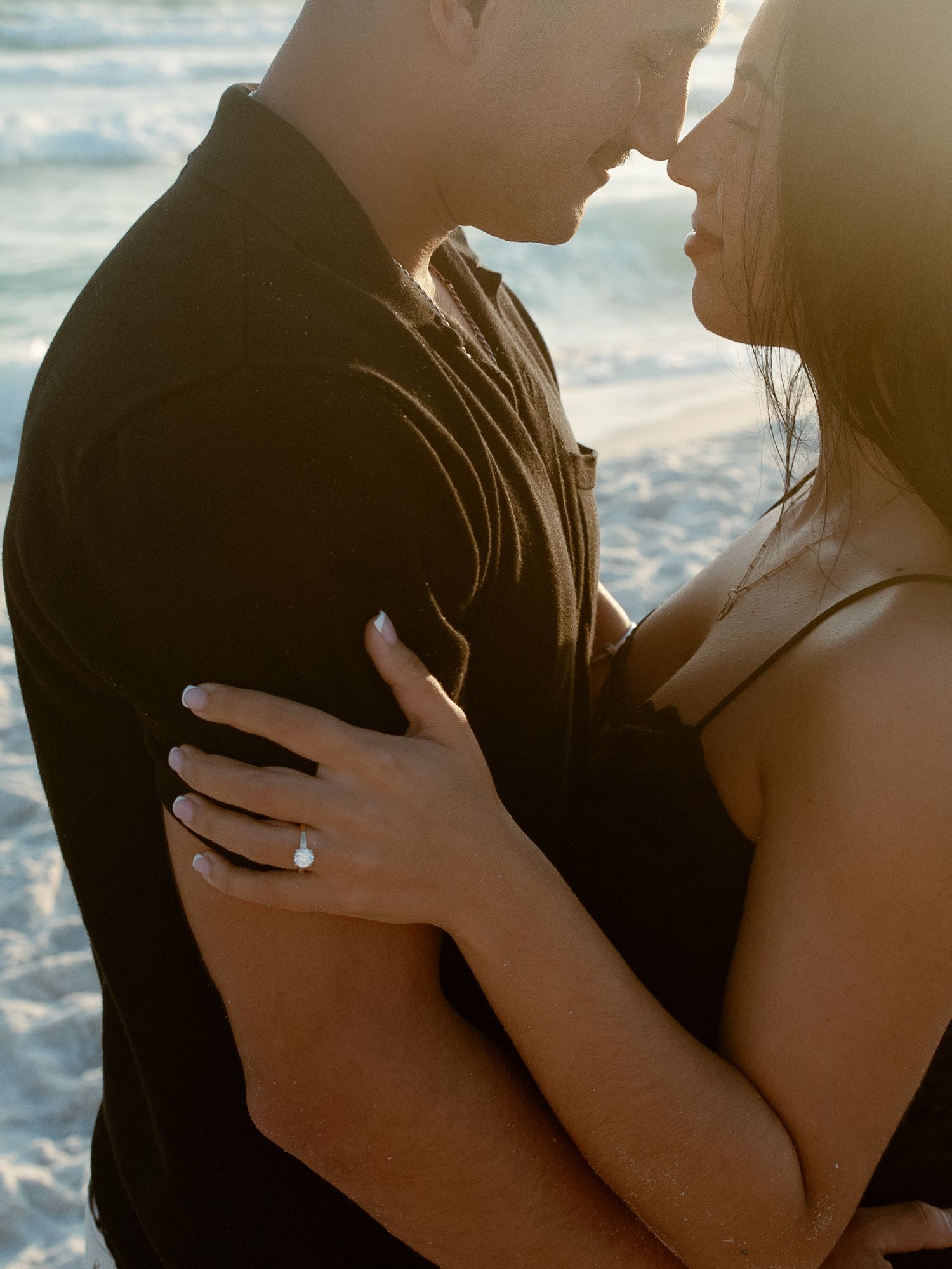 Romantic couple embraces in silhouette against ocean backdrop during golden hour sunset.