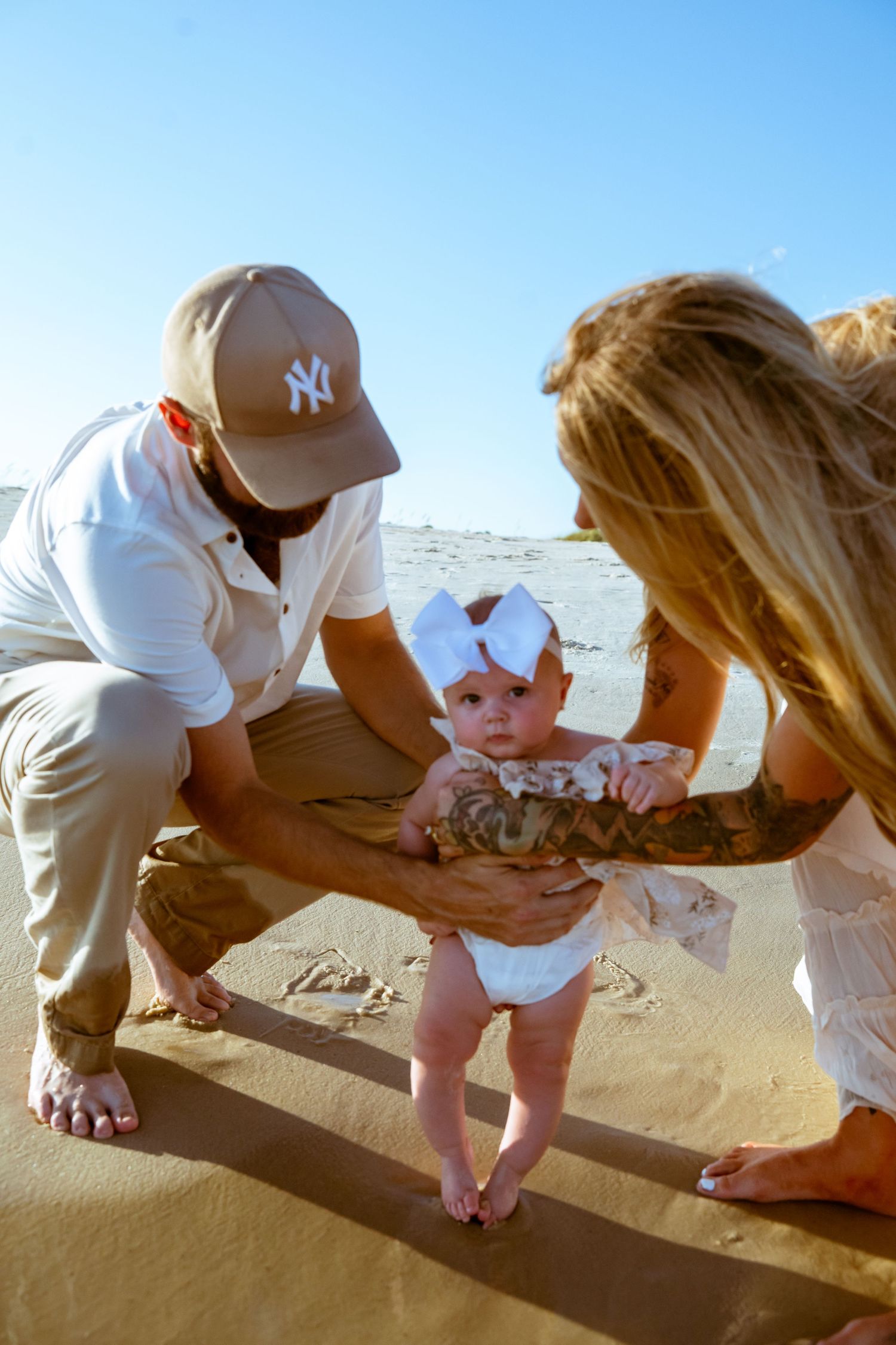 Parents introducing their baby to the sand and waves at a beach.