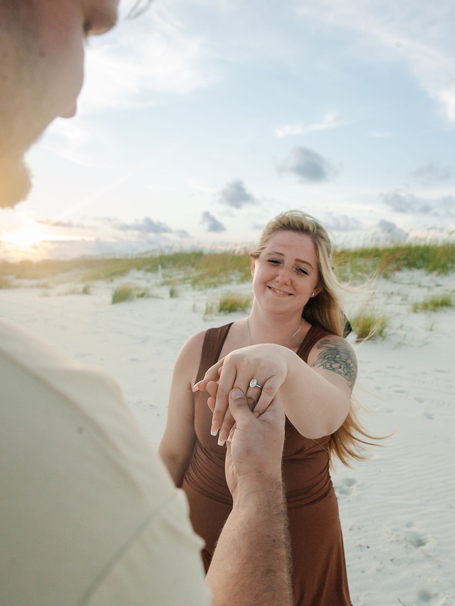 Series of photos showing a first-person view of someone reaching out towards a woman on a sandy beach at sunset.