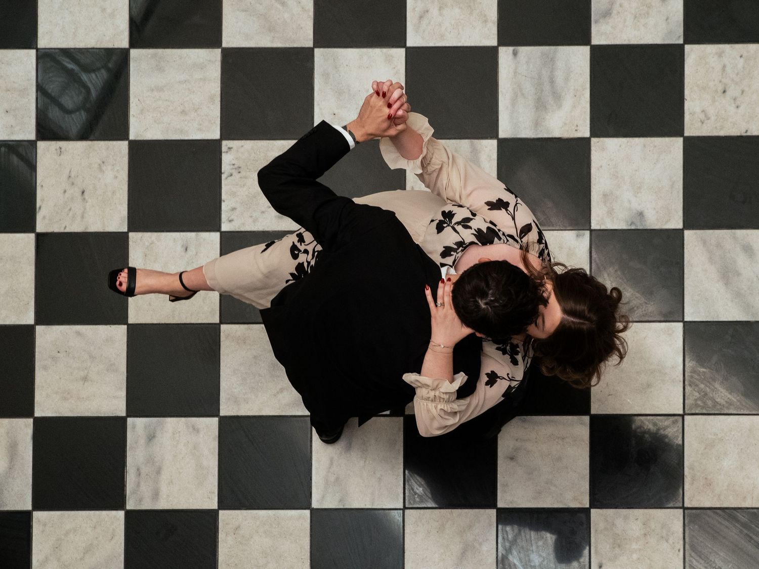 Aerial view of a couple dancing on a classic black and white checkered marble floor.