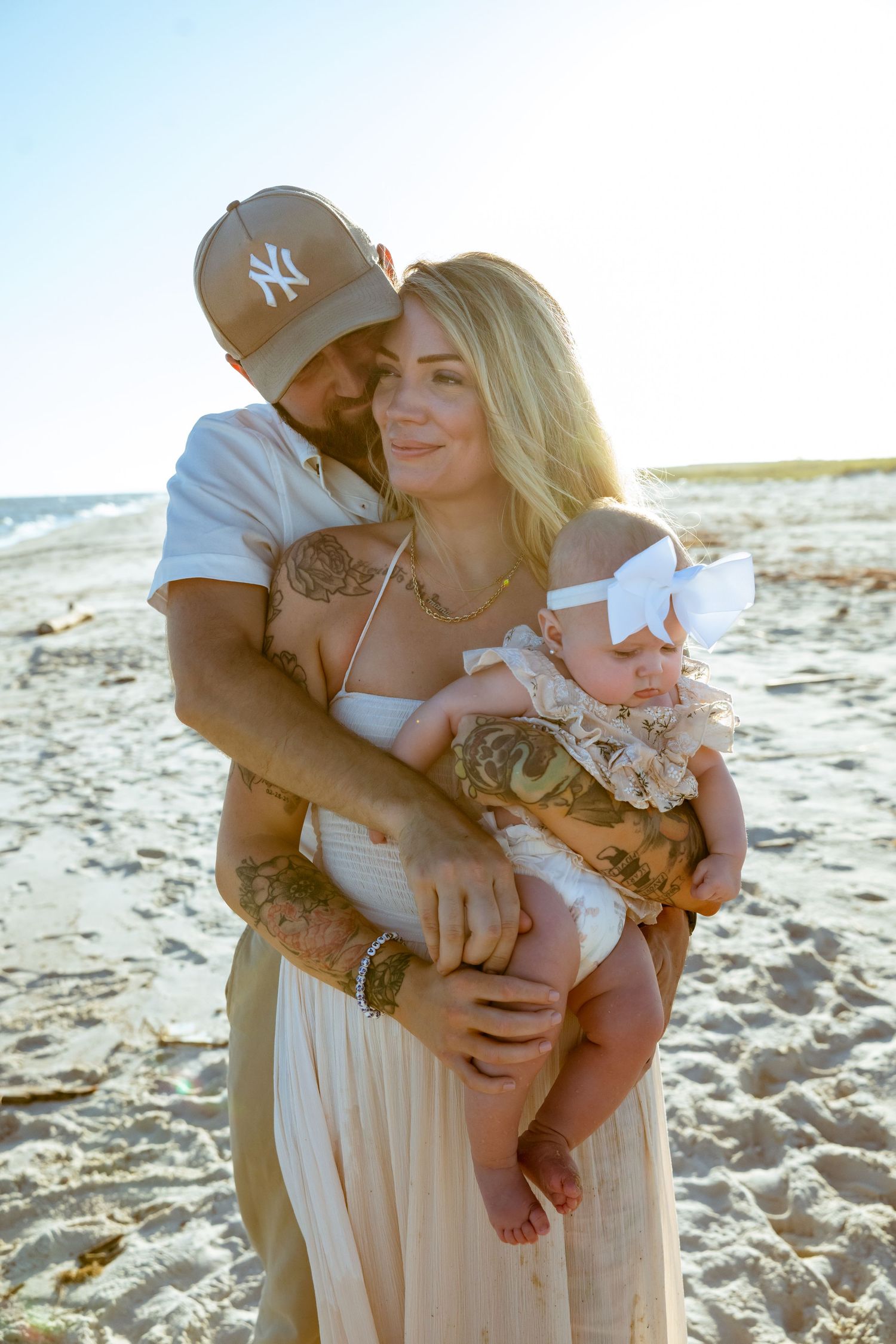 A tender family moment captured on a sandy beach at sunset.
