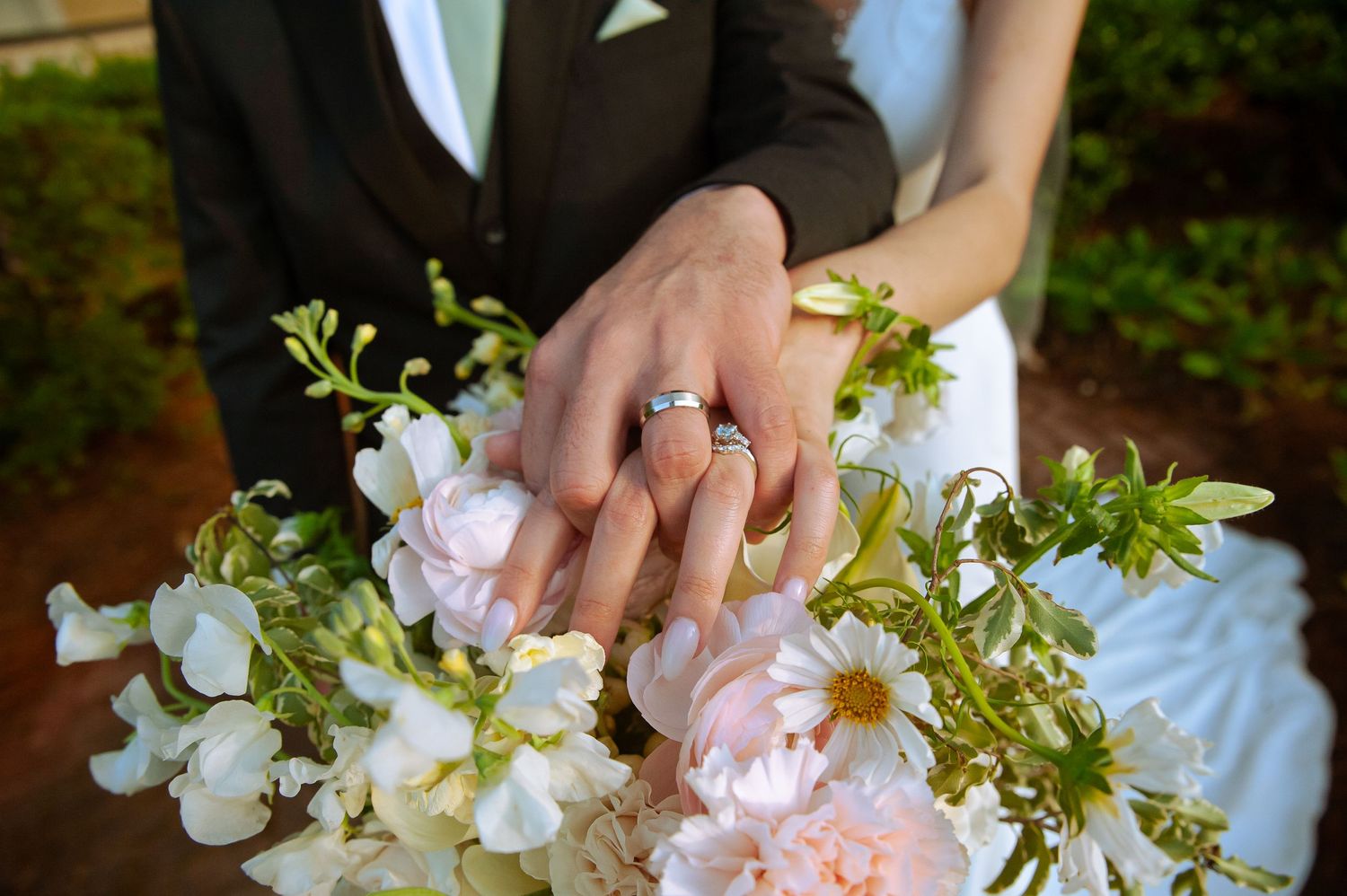 Wedding rings displayed with delicate white and pink flowers in a bridal bouquet.
