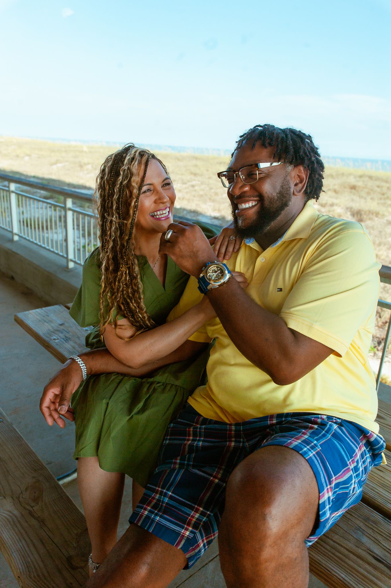 A joyful couple share intimate laughter and loving moments together while sitting on a wooden deck.
