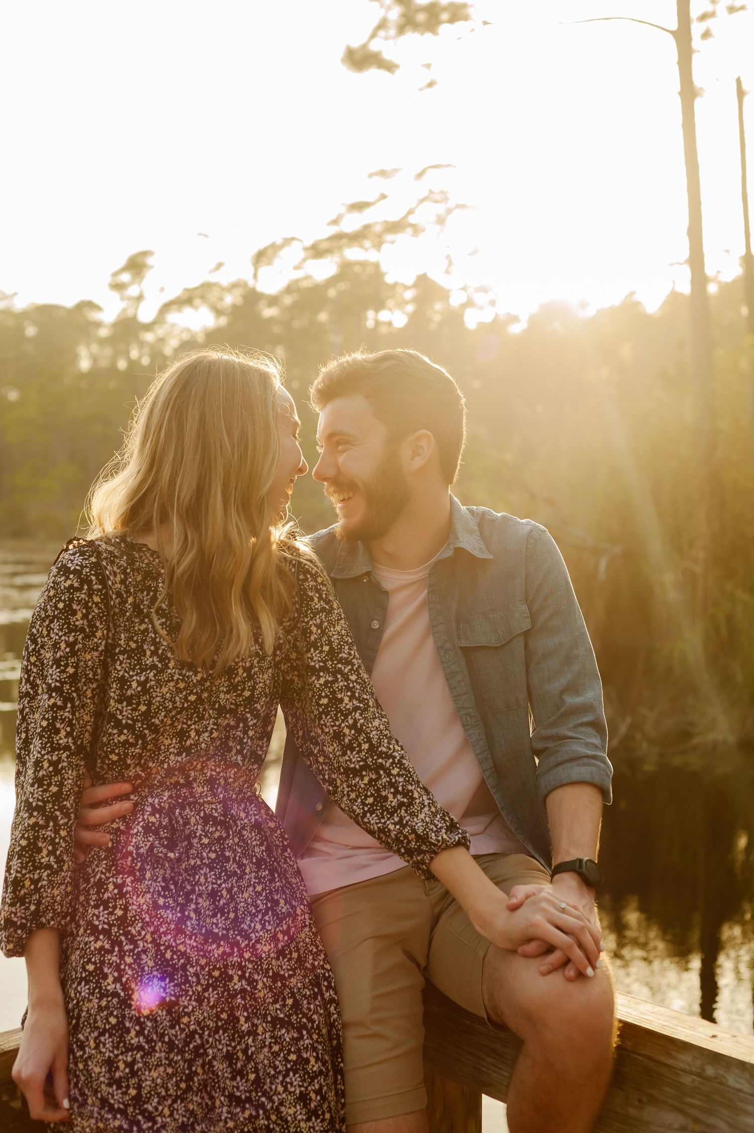 A couple shares intimate moment during golden hour by waterfront.