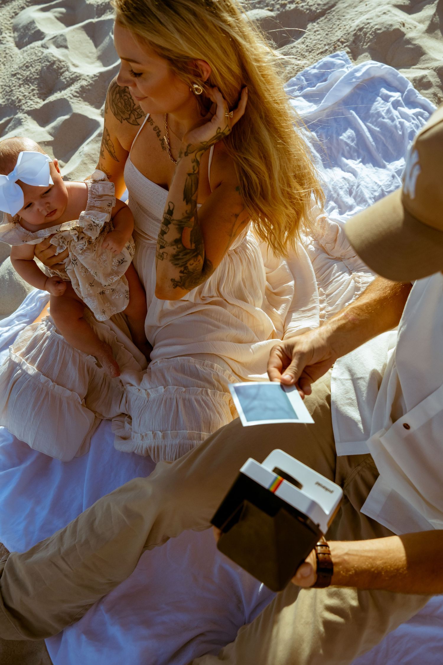 A candid beach moment with a family looking at photos together on the sand.