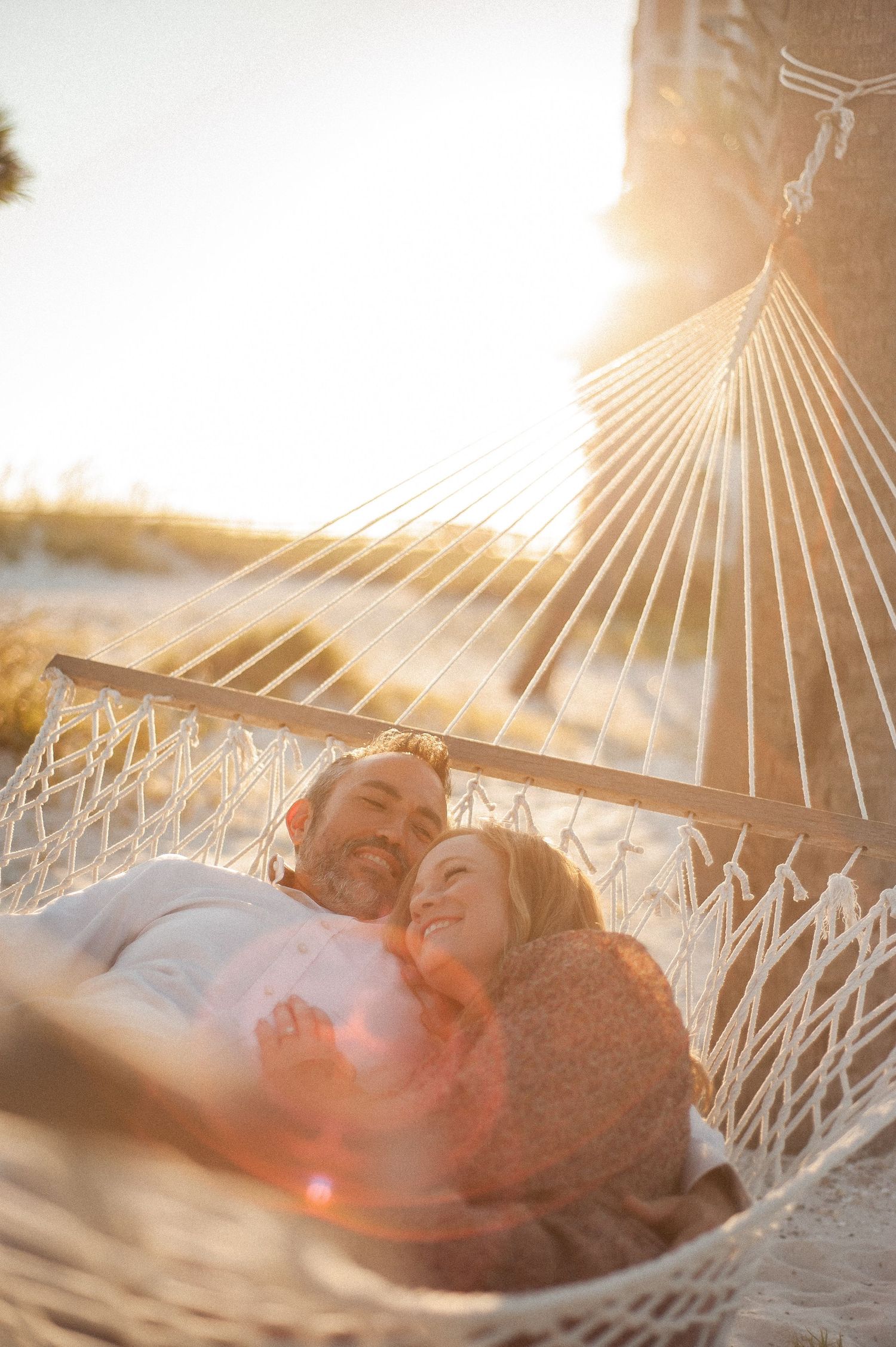 A couple relaxing together in a hammock during golden hour sunlight.