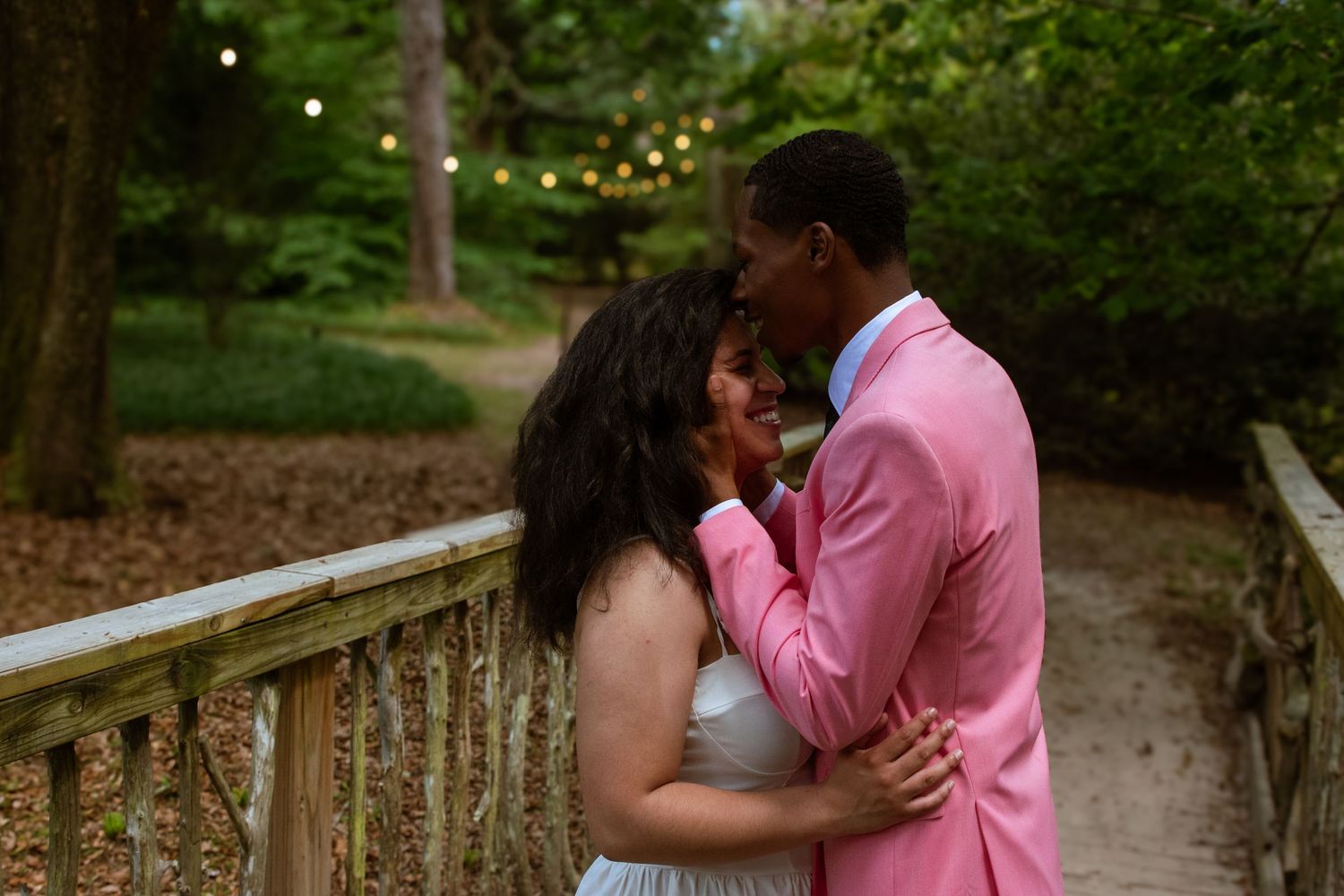 A romantic evening moment shared between a couple on a bridge with string lights.