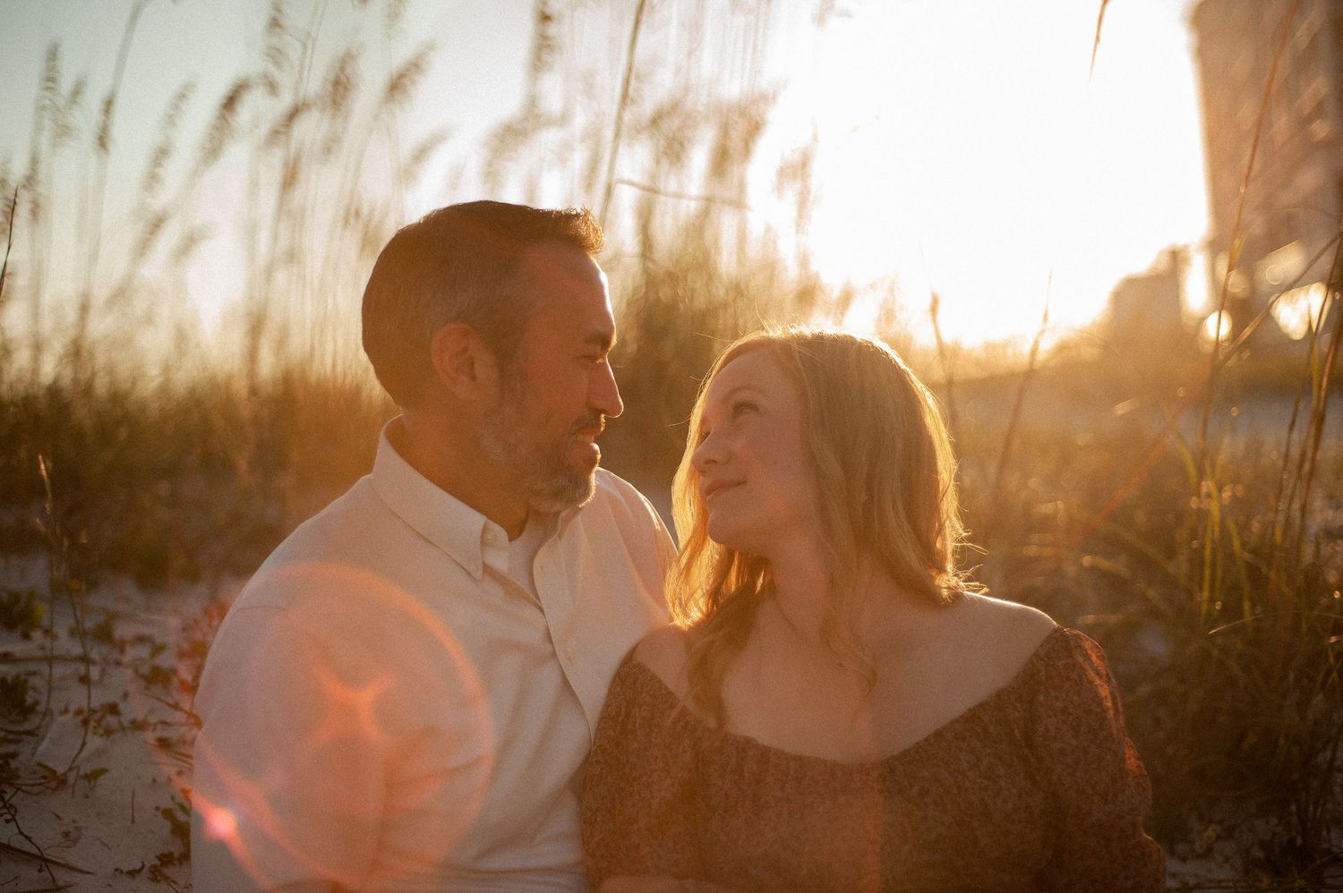 Intimate sunset portraits captured among beach grass and dunes.