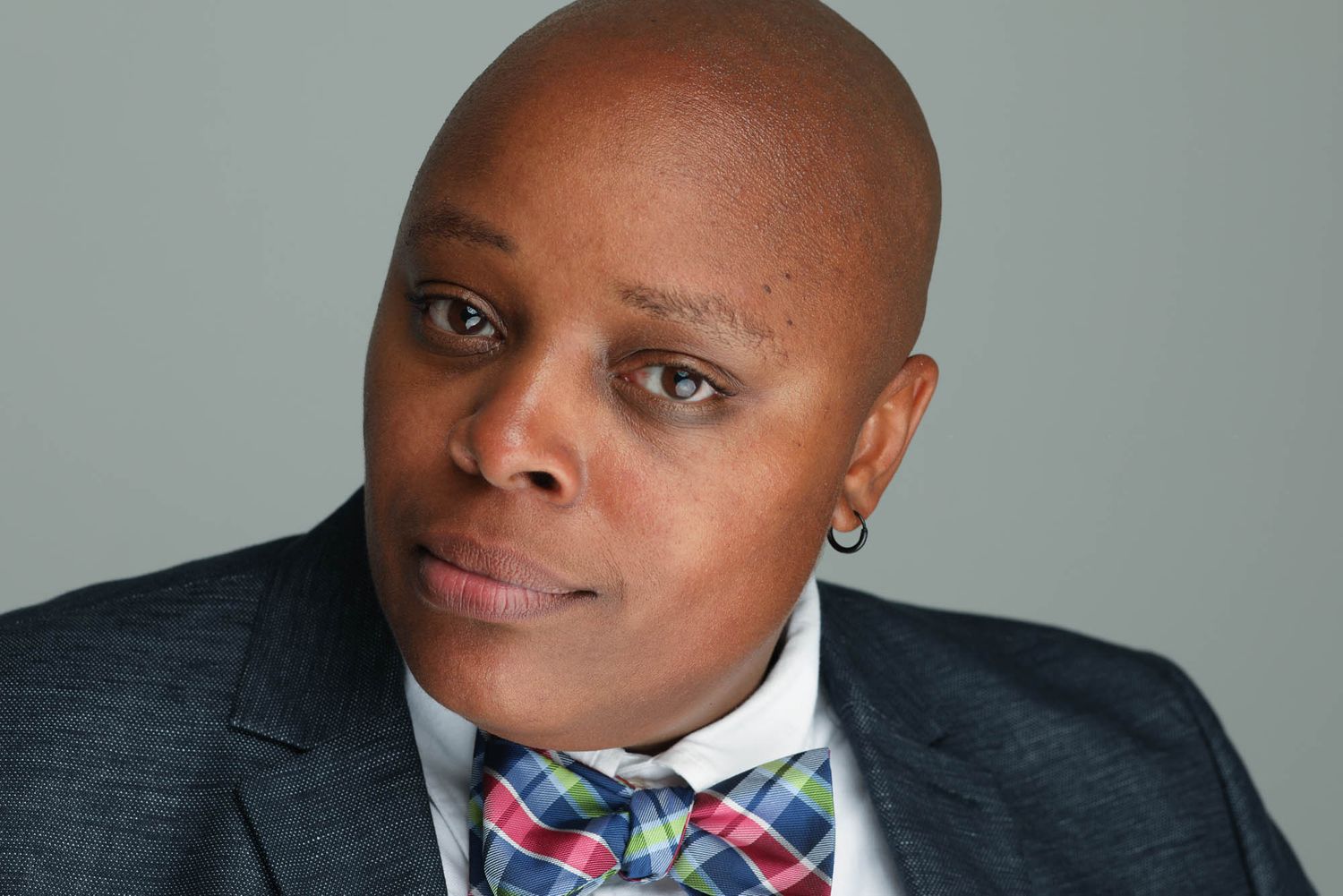 Professional headshot of someone wearing a colorful bowtie and dark suit against a gray background.