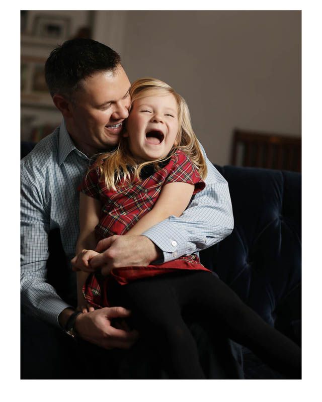 A heartwarming candid moment of shared laughter between a parent and child sitting together on a blue couch.