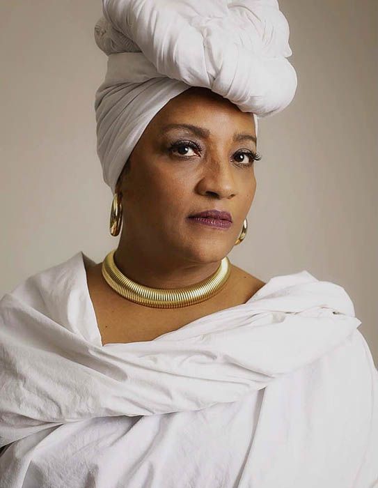 Portrait series showing figure in white head wrap and gold turtleneck from different angles with neutral background.