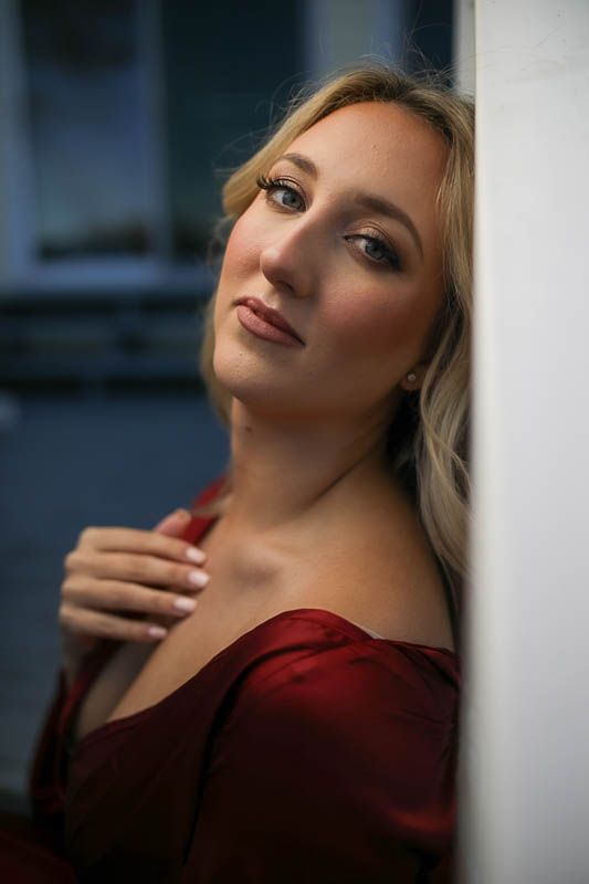 Artistic fashion portrait of a woman in red clothing against a dark dramatic background.