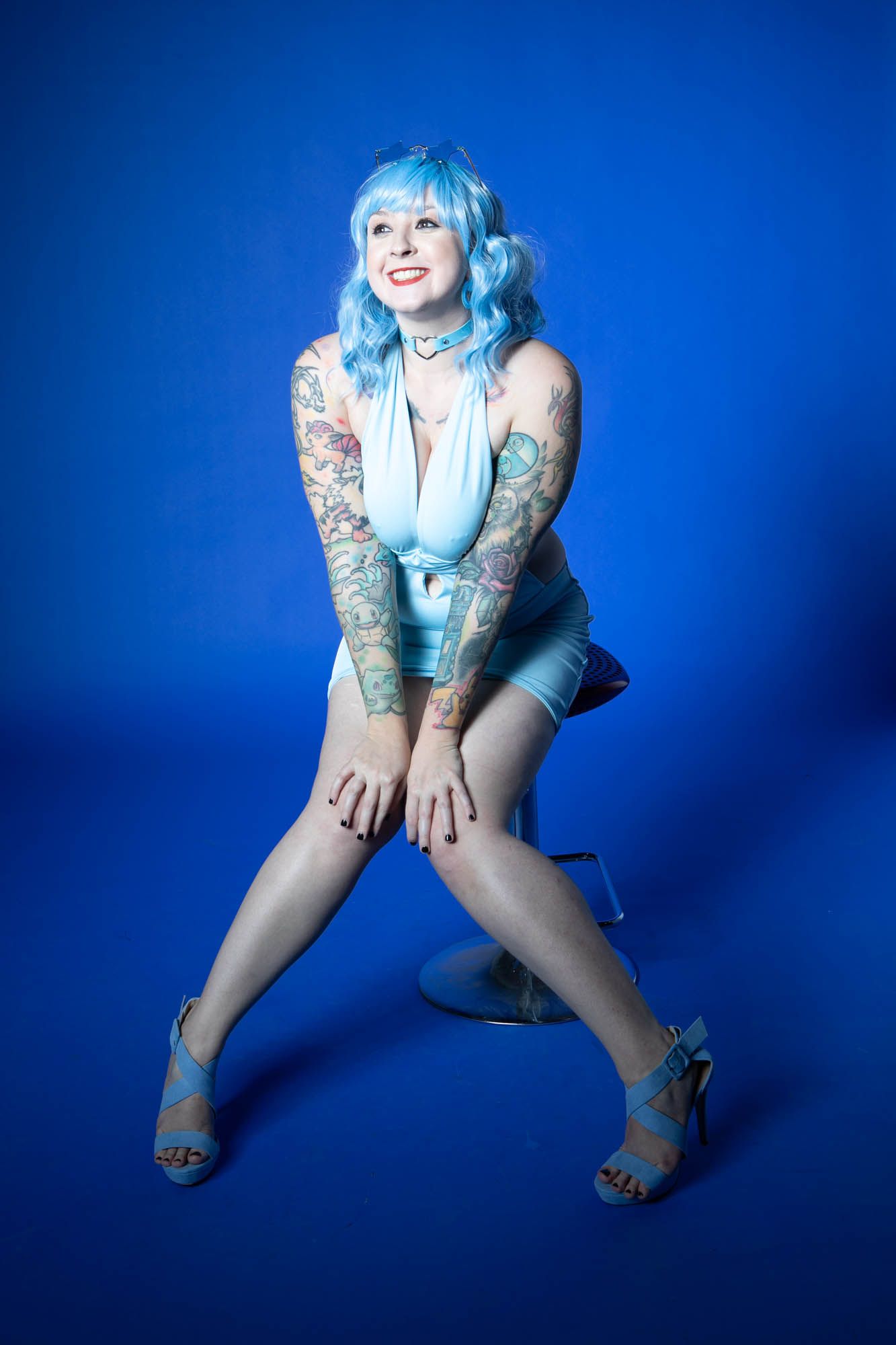 A dynamic photo sequence shows someone in a blue outfit and tattoos posing playfully against a bright blue background.