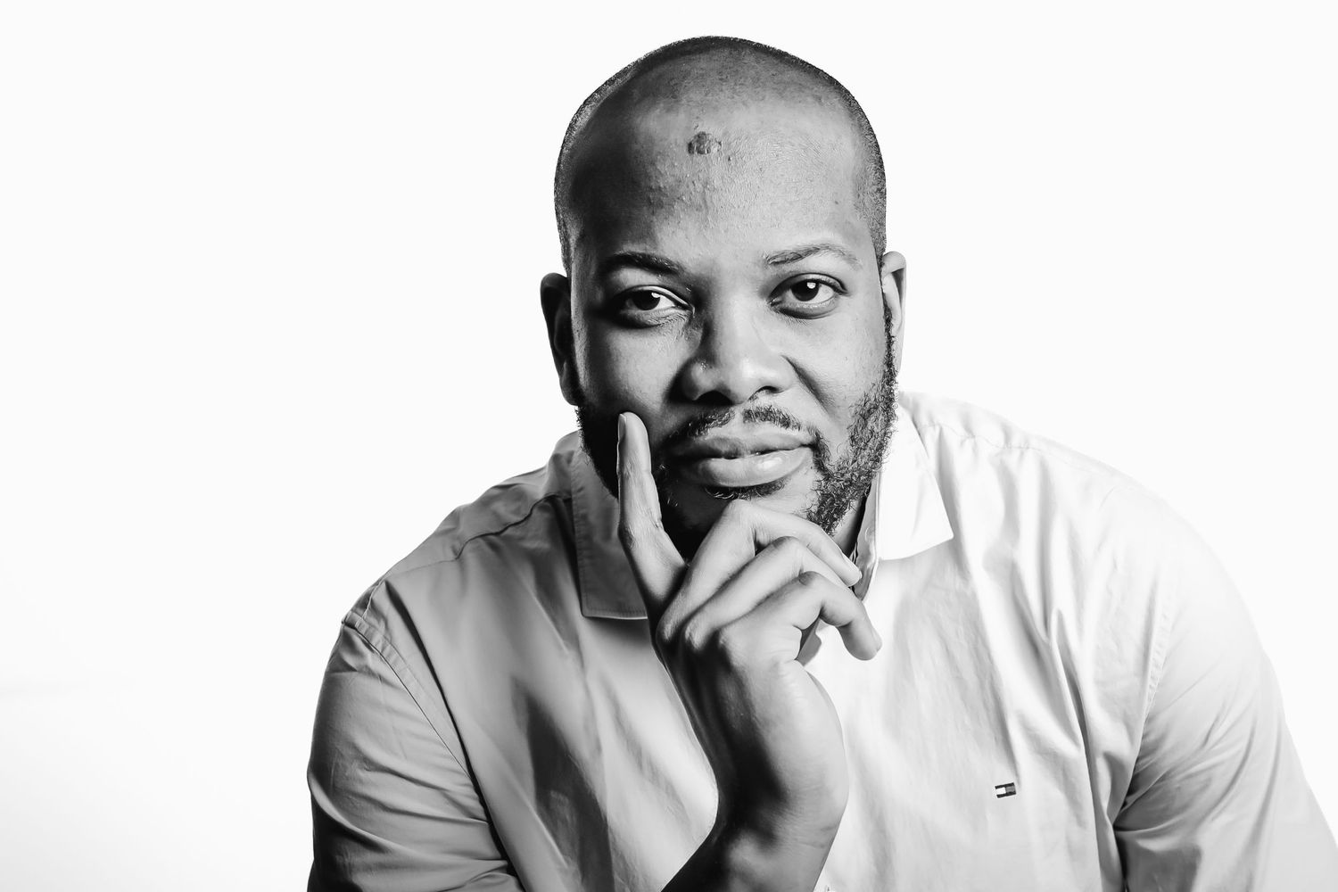Black and white portrait of a person in thoughtful pose against white background.