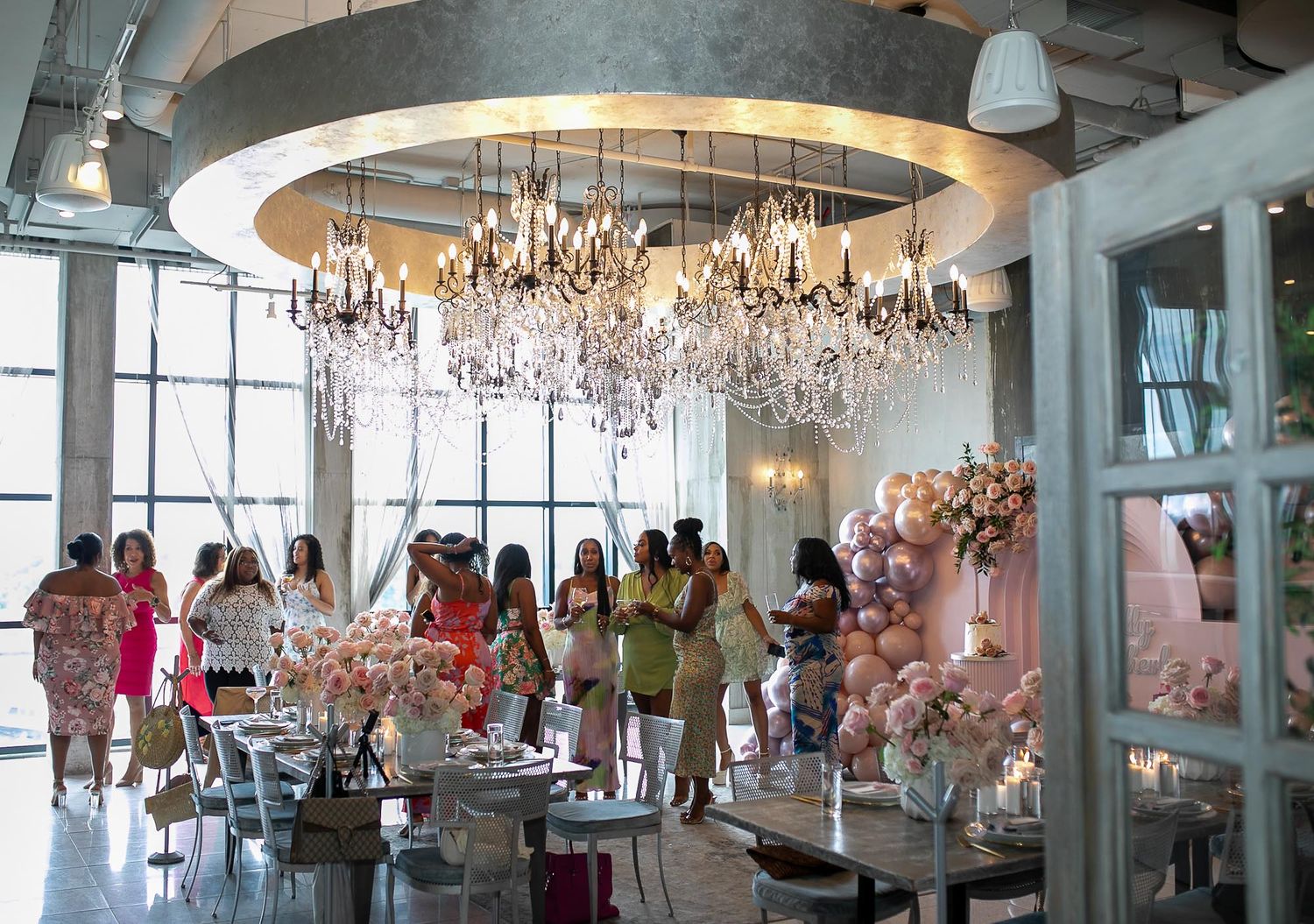 Elegant chandeliers hang from the ceiling in a modern restaurant dining room filled with patrons enjoying their meals.