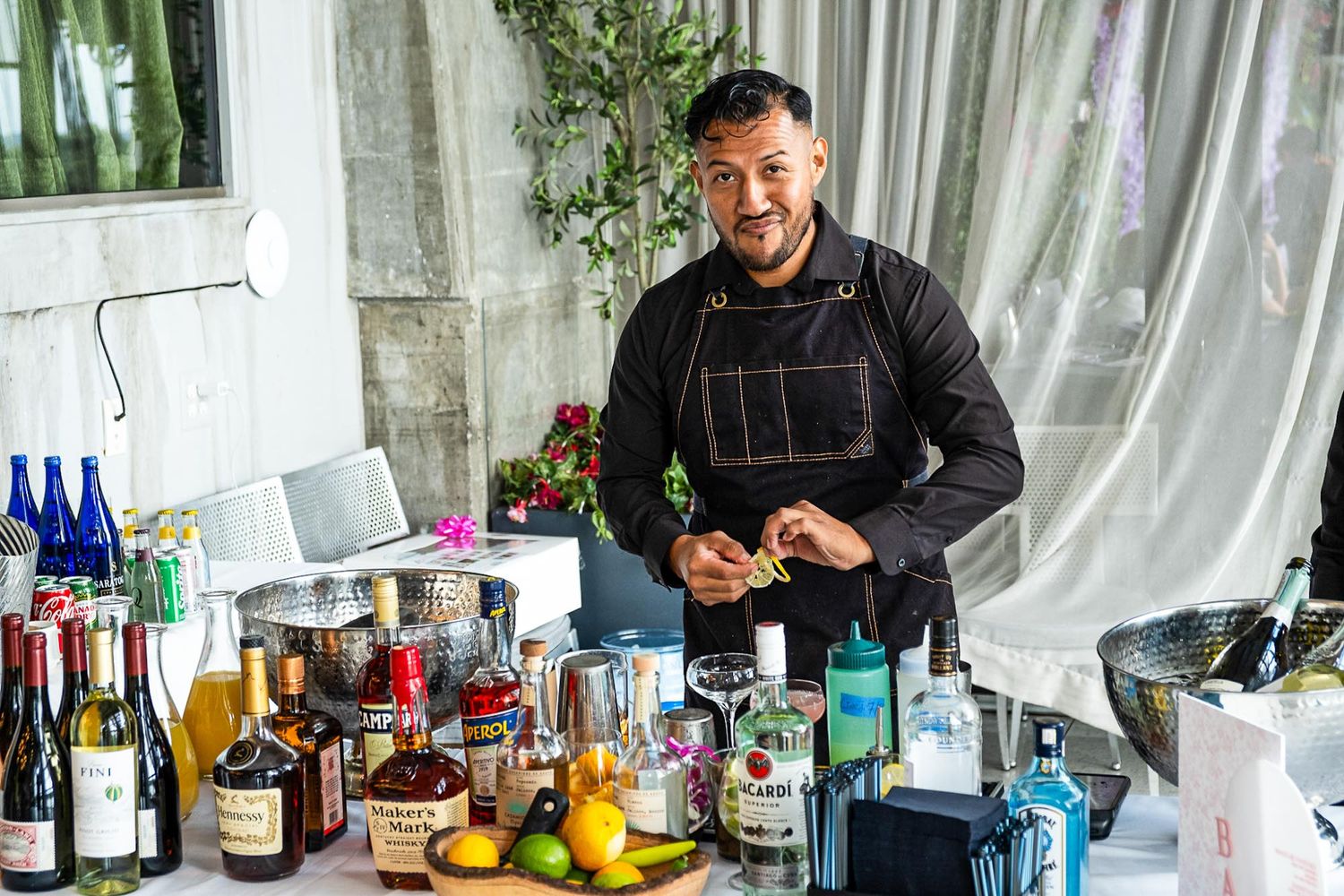 Bar setup with various bottles and cocktail mixing equipment in bright indoor setting.