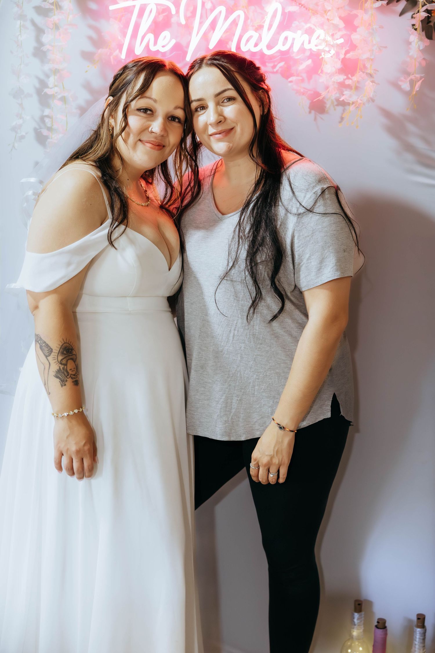 Friends celebrating under pink neon sign with floral decorations.