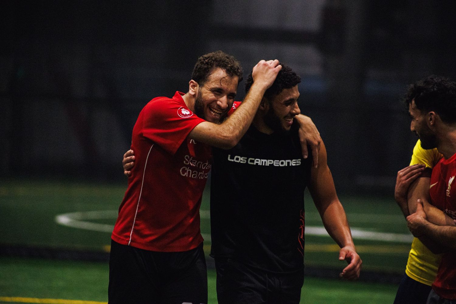 Teammates celebrating a goal at an indoor Twin Cities soccer match