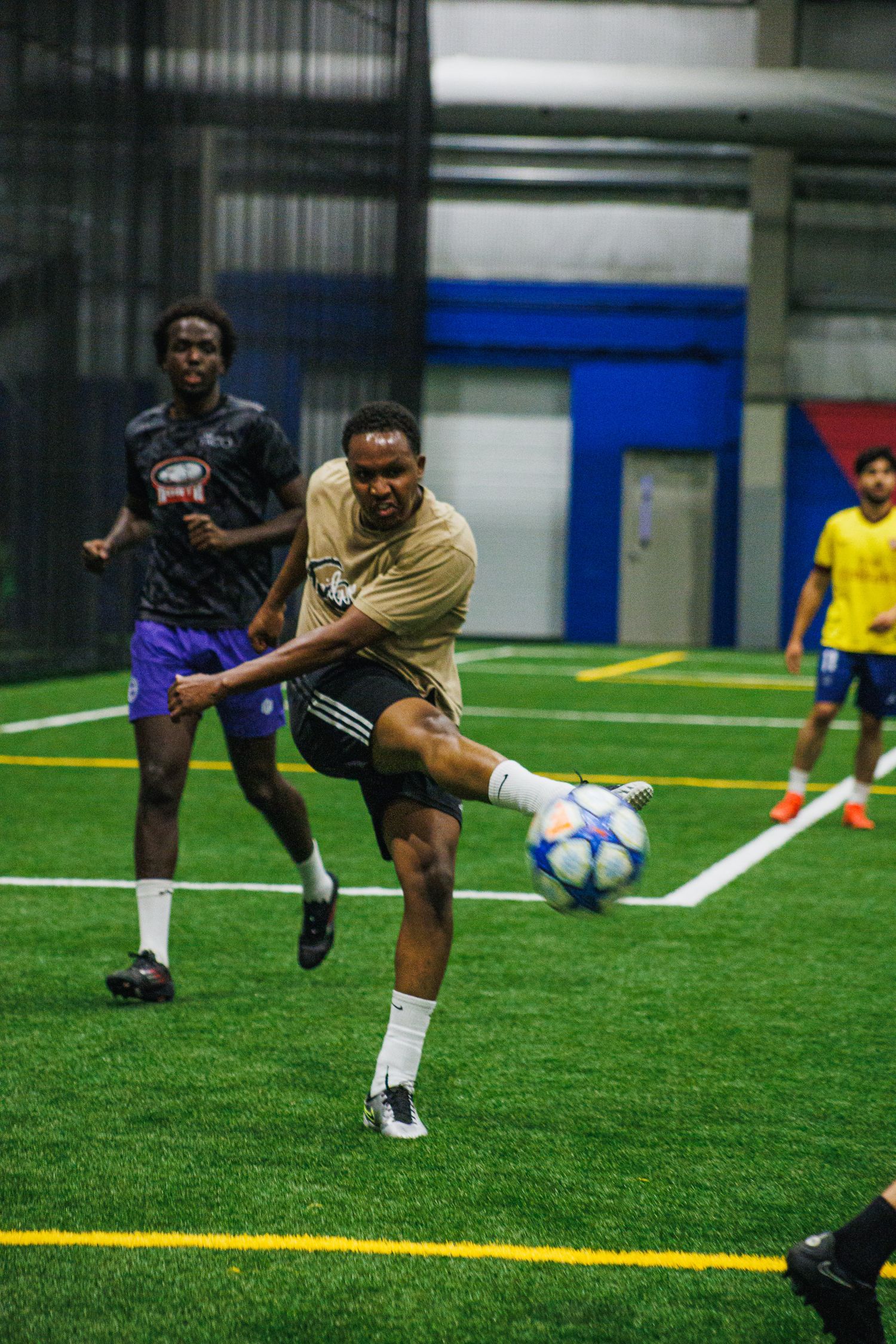 Two players chasing down the ball in a Twin Cities indoor soccer match