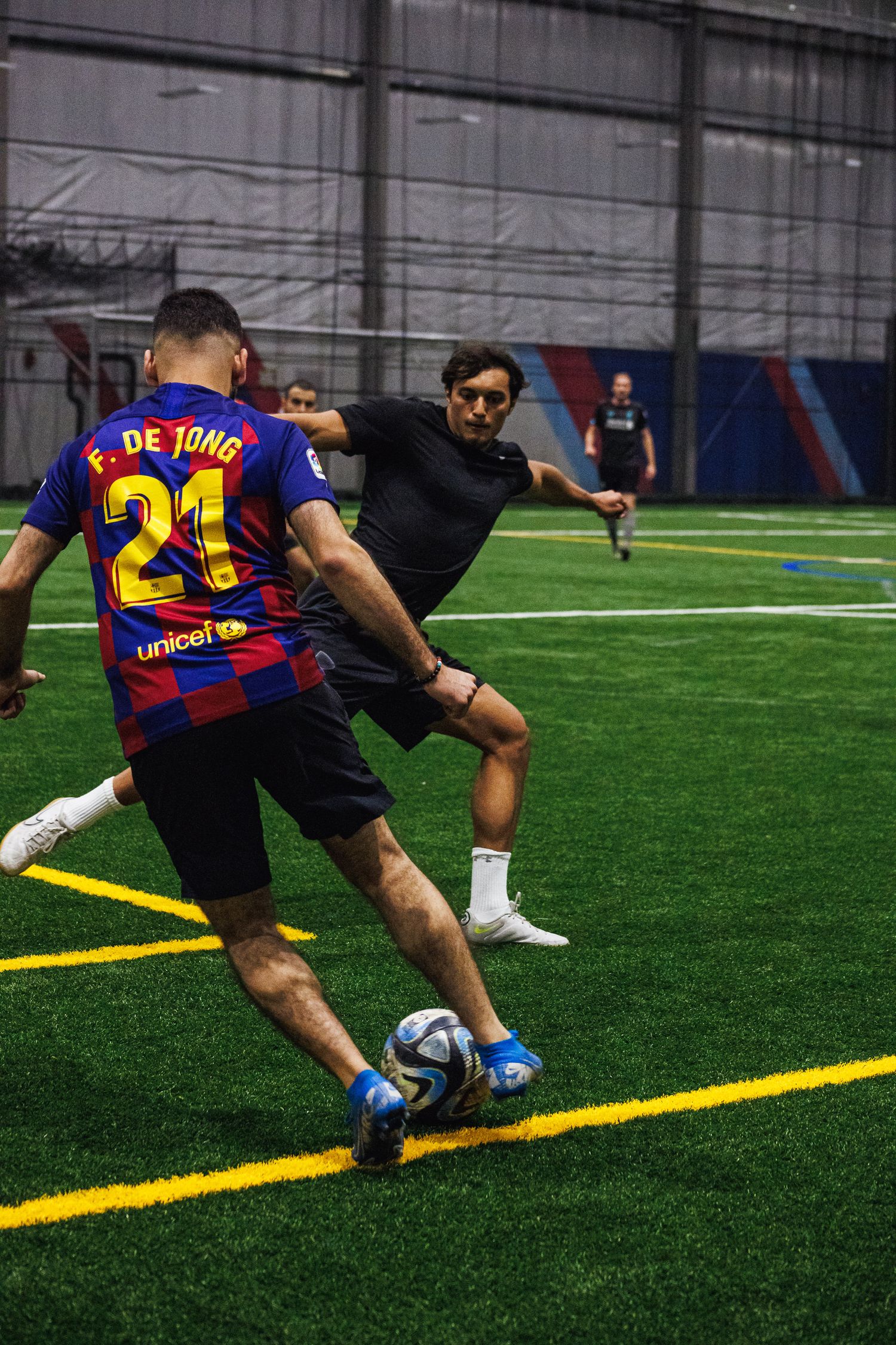 Forward dribbling past a defender in an indoor Minneapolis soccer game
