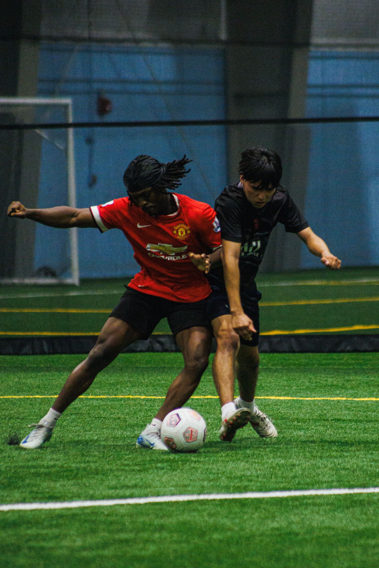 Two players racing to the ball in an indoor Twin Cities soccer game
