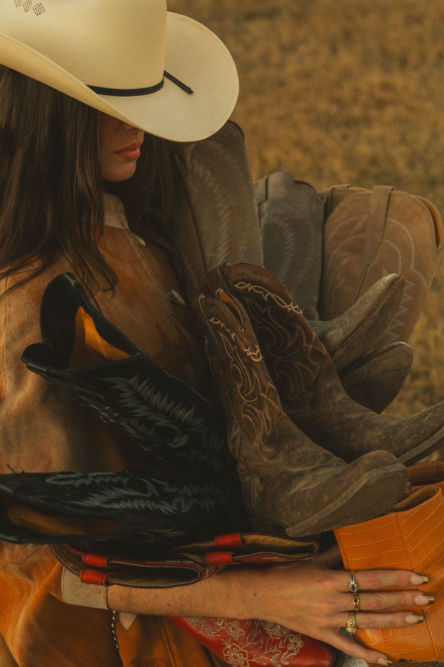 Close-up of various western boots with intricate details in warm lighting.