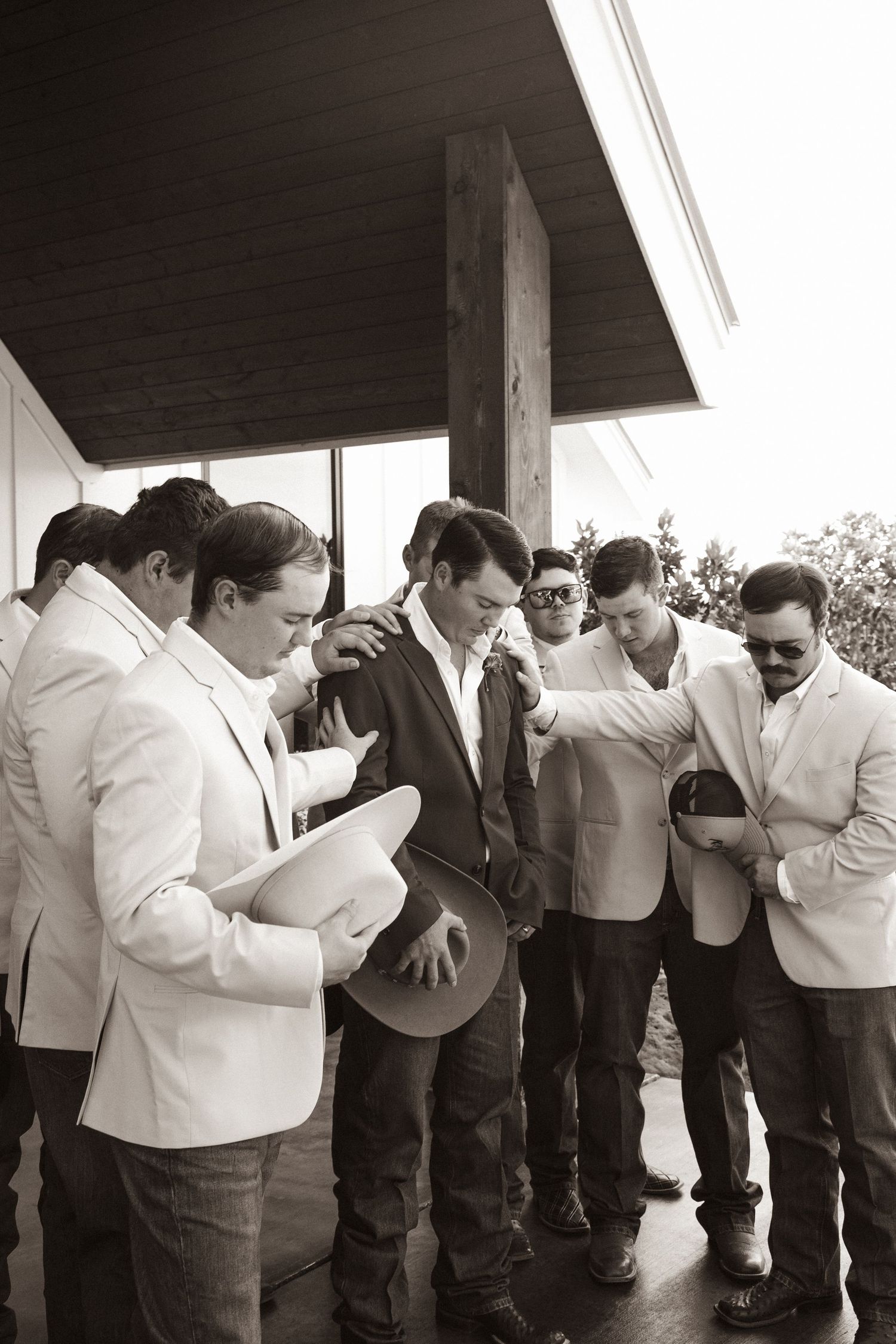 Wedding party members share an emotional moment during group prayer.