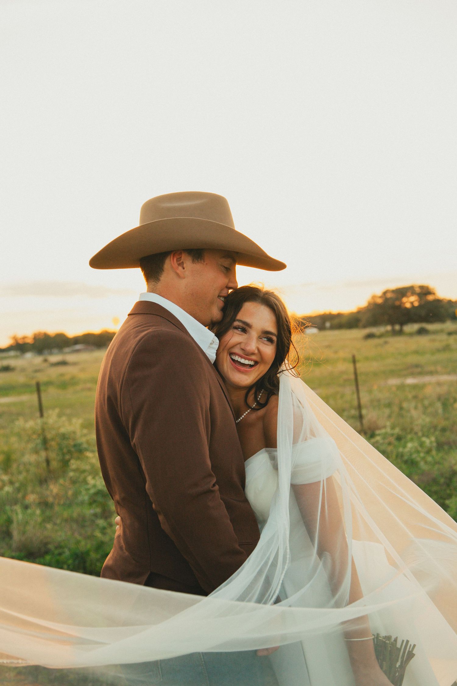 A joyful wedding portrait showing a laughing couple sharing an intimate moment in golden light.