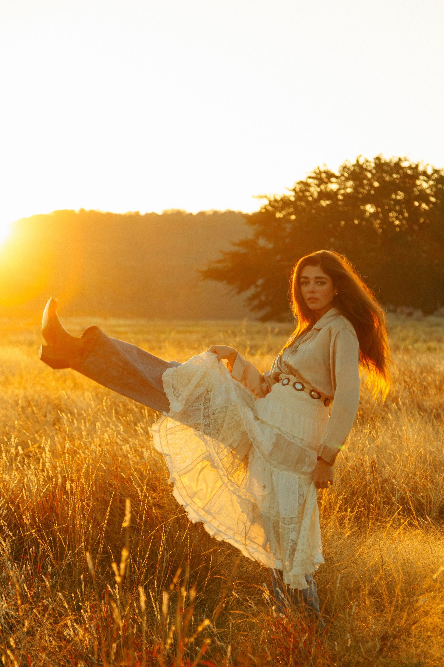 Ethereal movement of white dress captured in golden sunlit field during sunset.