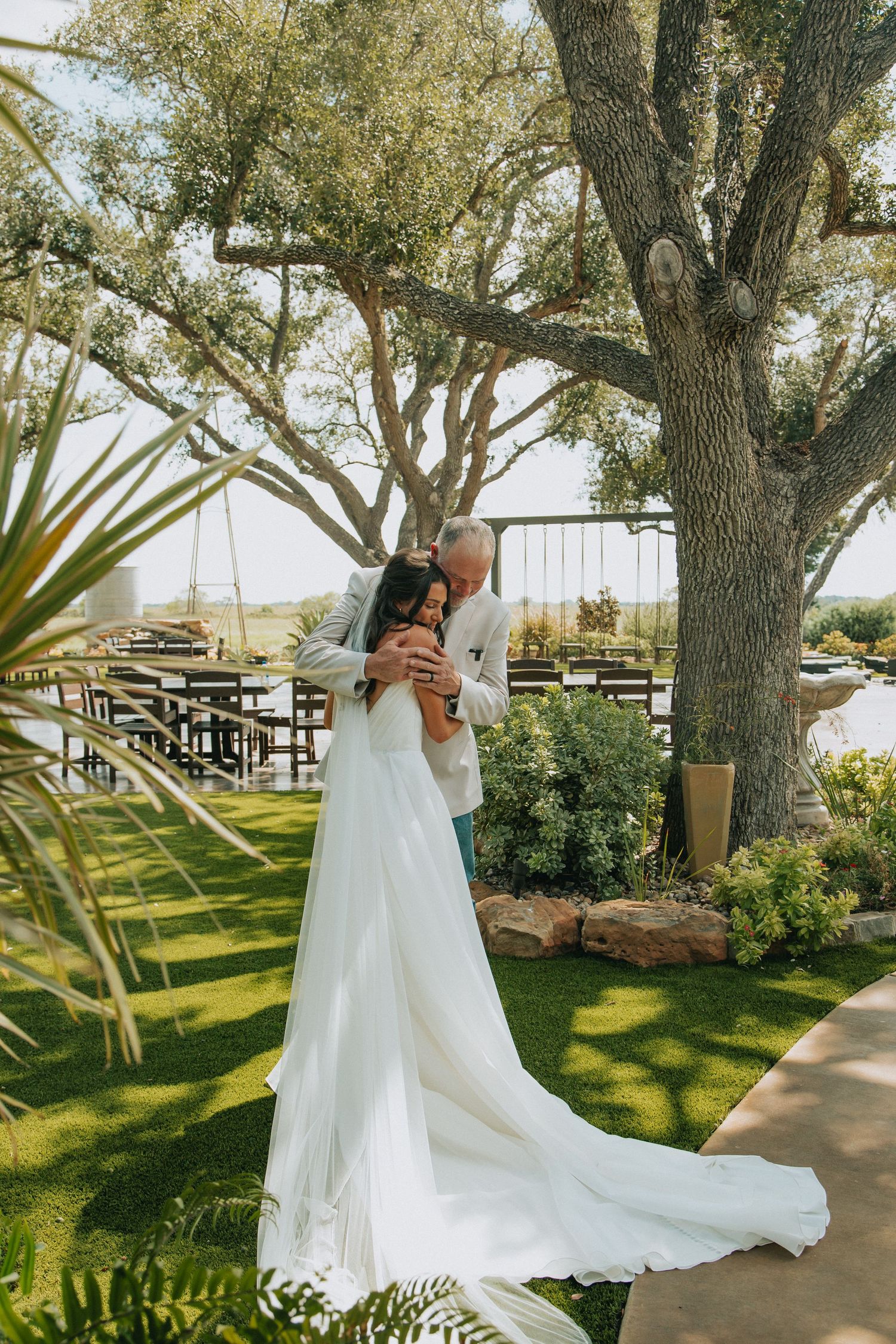 A flowing white wedding dress captured in motion against a backdrop of trees and greenery.