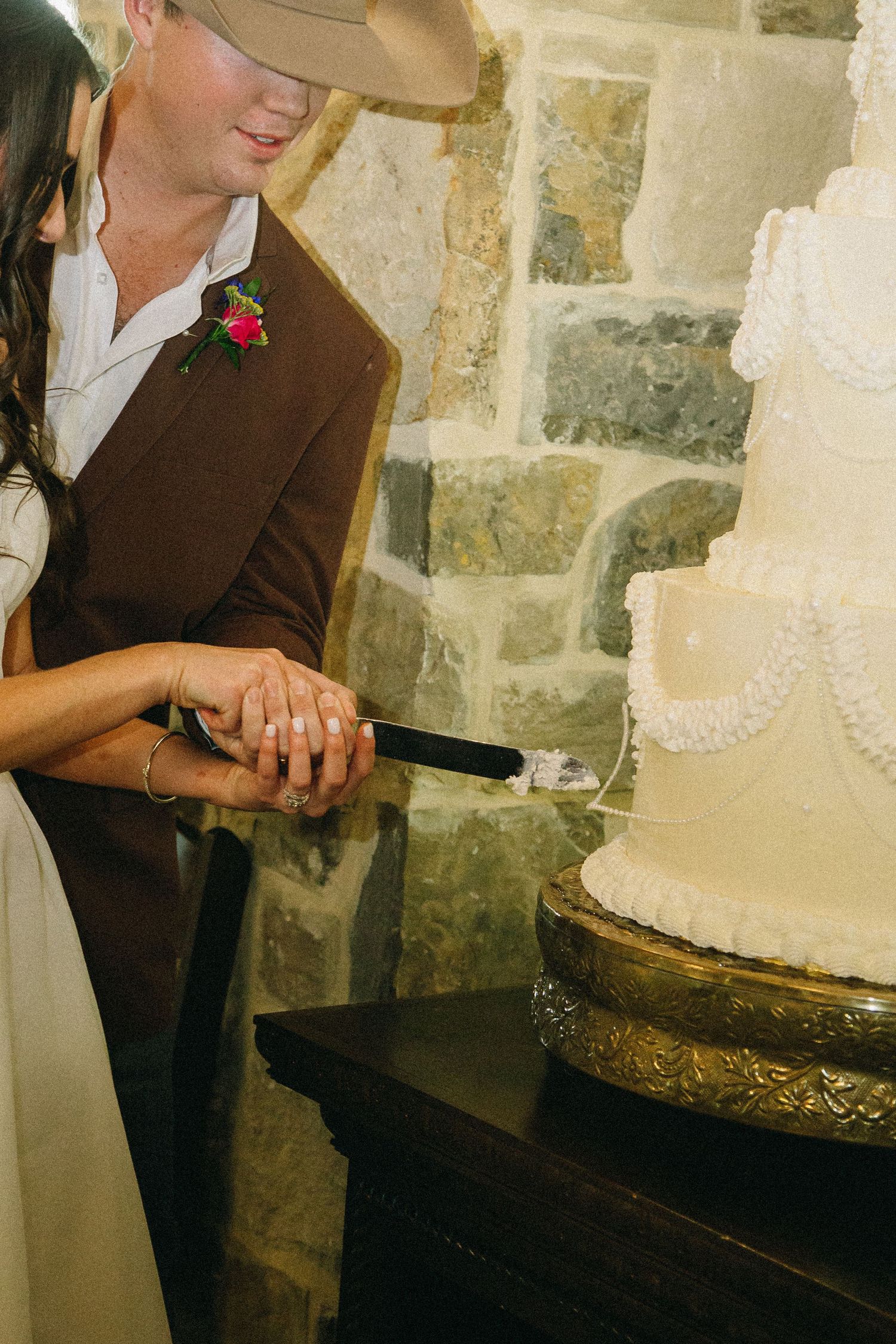 Close-up of a newly married couple cutting an elegant white wedding cake at a wedding reception.