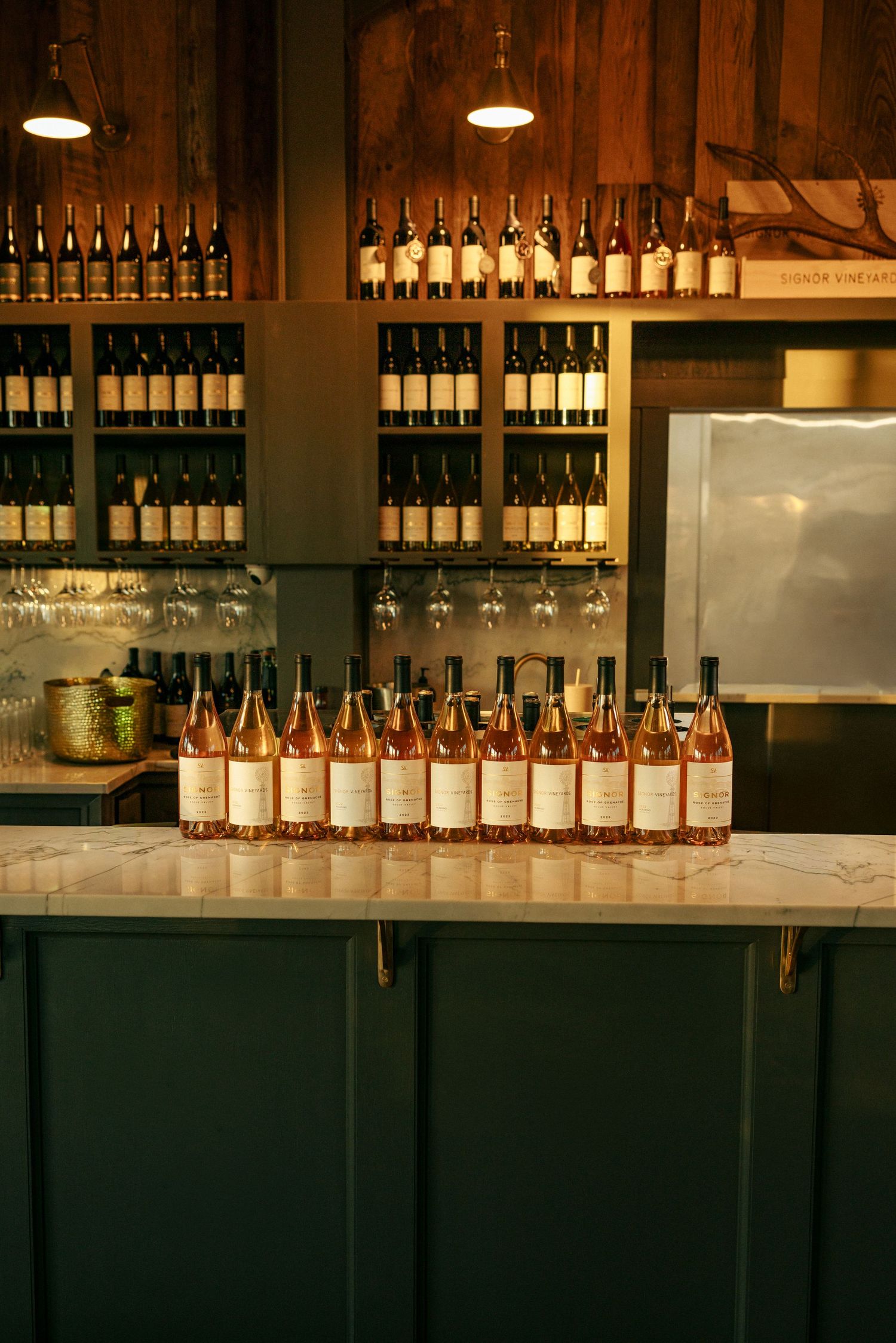 Well-stocked wine bar display with bottles and glasses arranged on shelving.