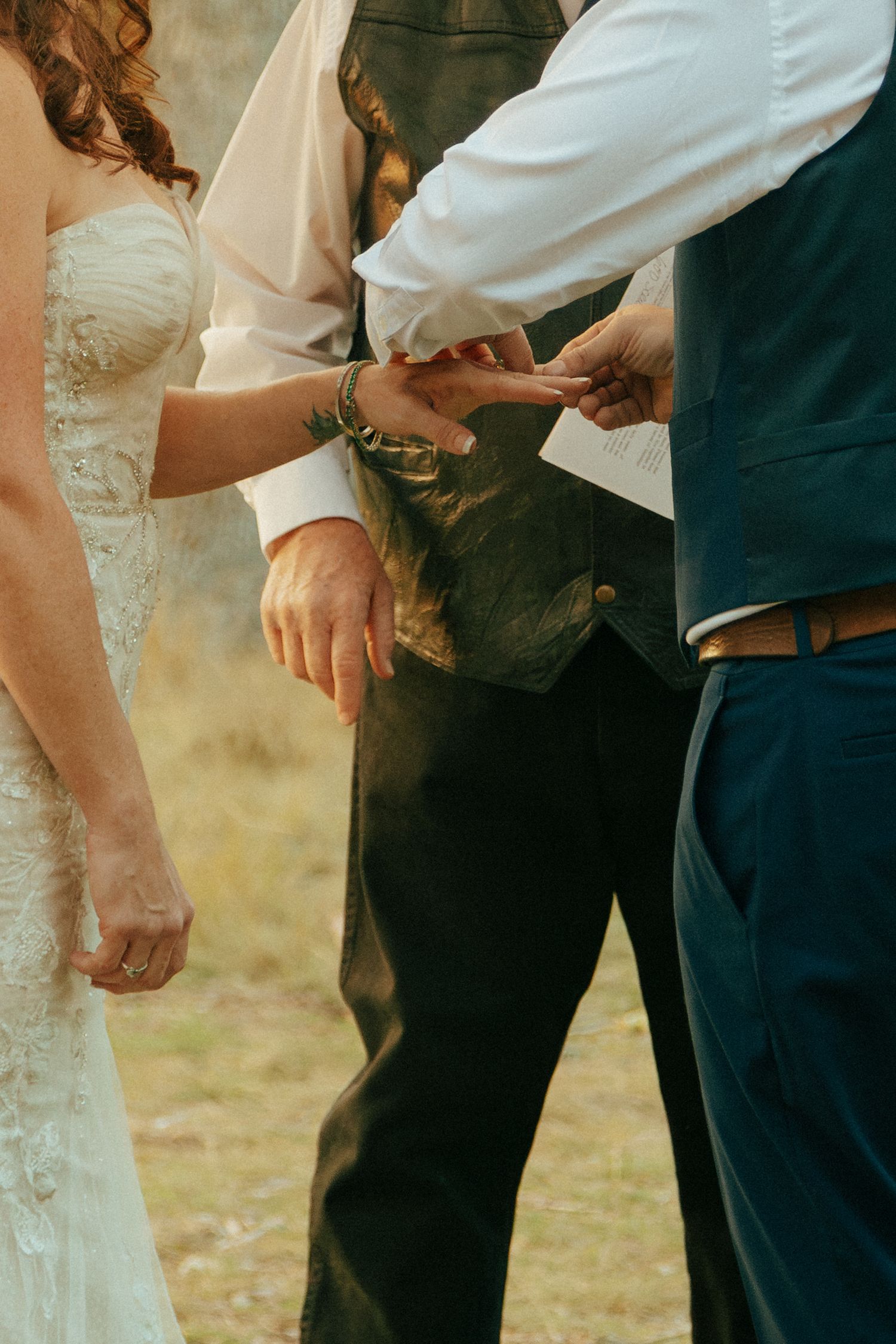 A close-up shot of the groom placing a wedding band on the bride during a wedding ceremony.