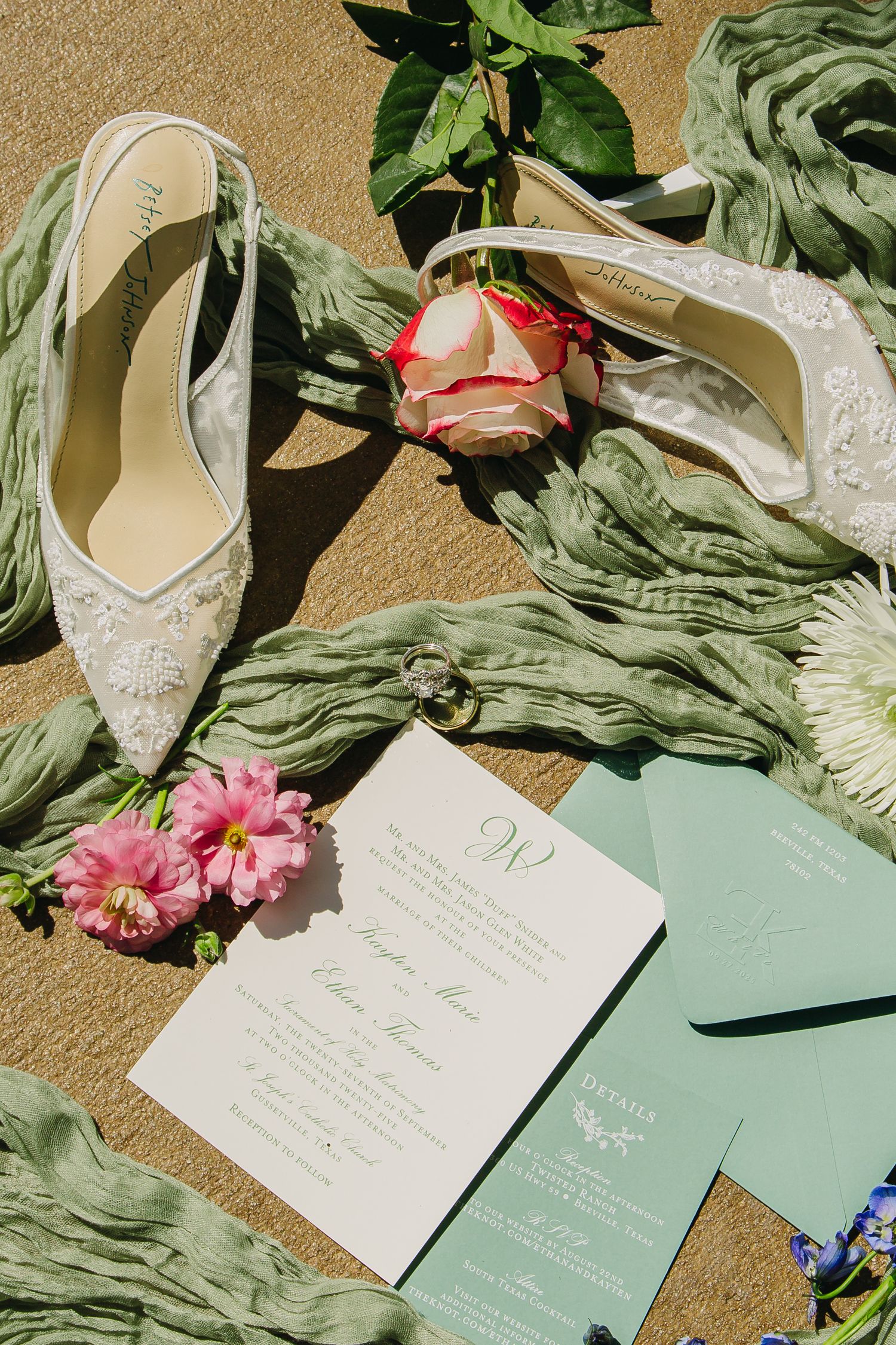 Wedding invitation suite with lace heels and pink roses on beige background.