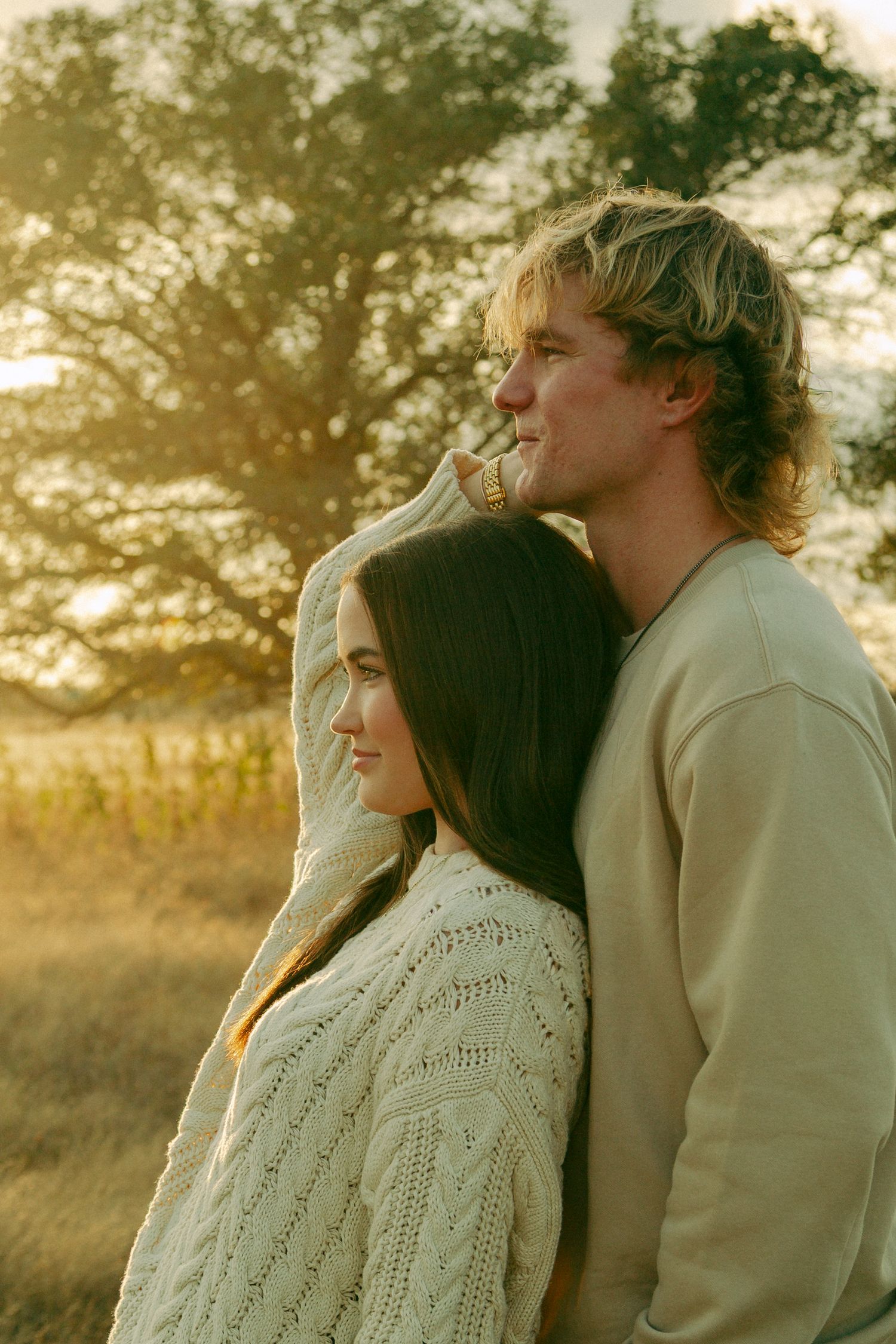 Couple sharing an intimate moment at sunset in a field.