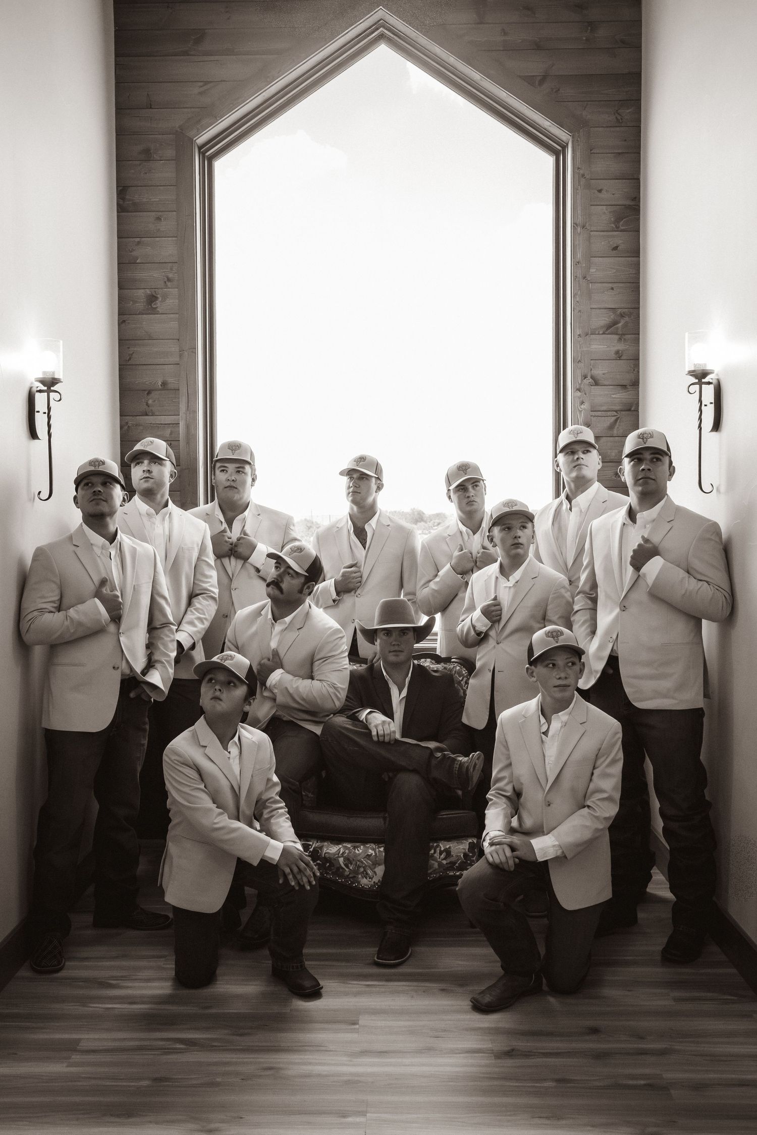 Groomsmen pose in chapel with dramatic arched window.
