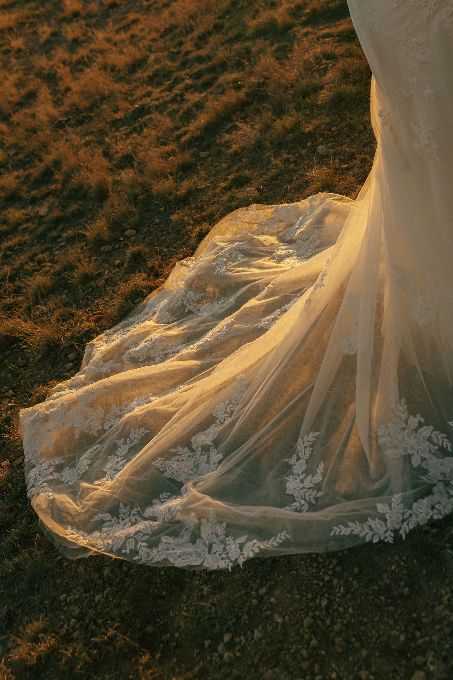 Intricate lace details of a wedding dress train illuminated by golden sunset light.