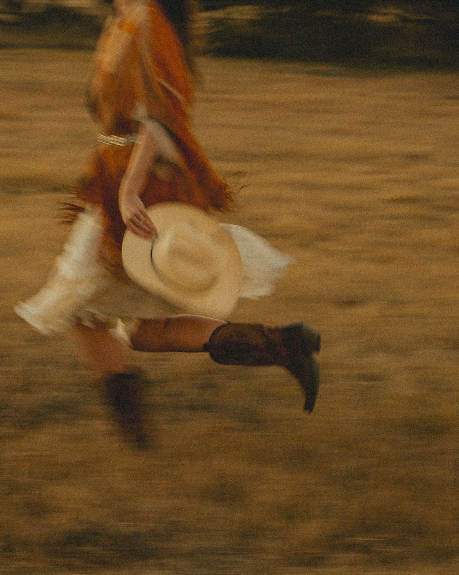 Motion-blurred sequence of someone running through a field wearing a fringed jacket at dusk.