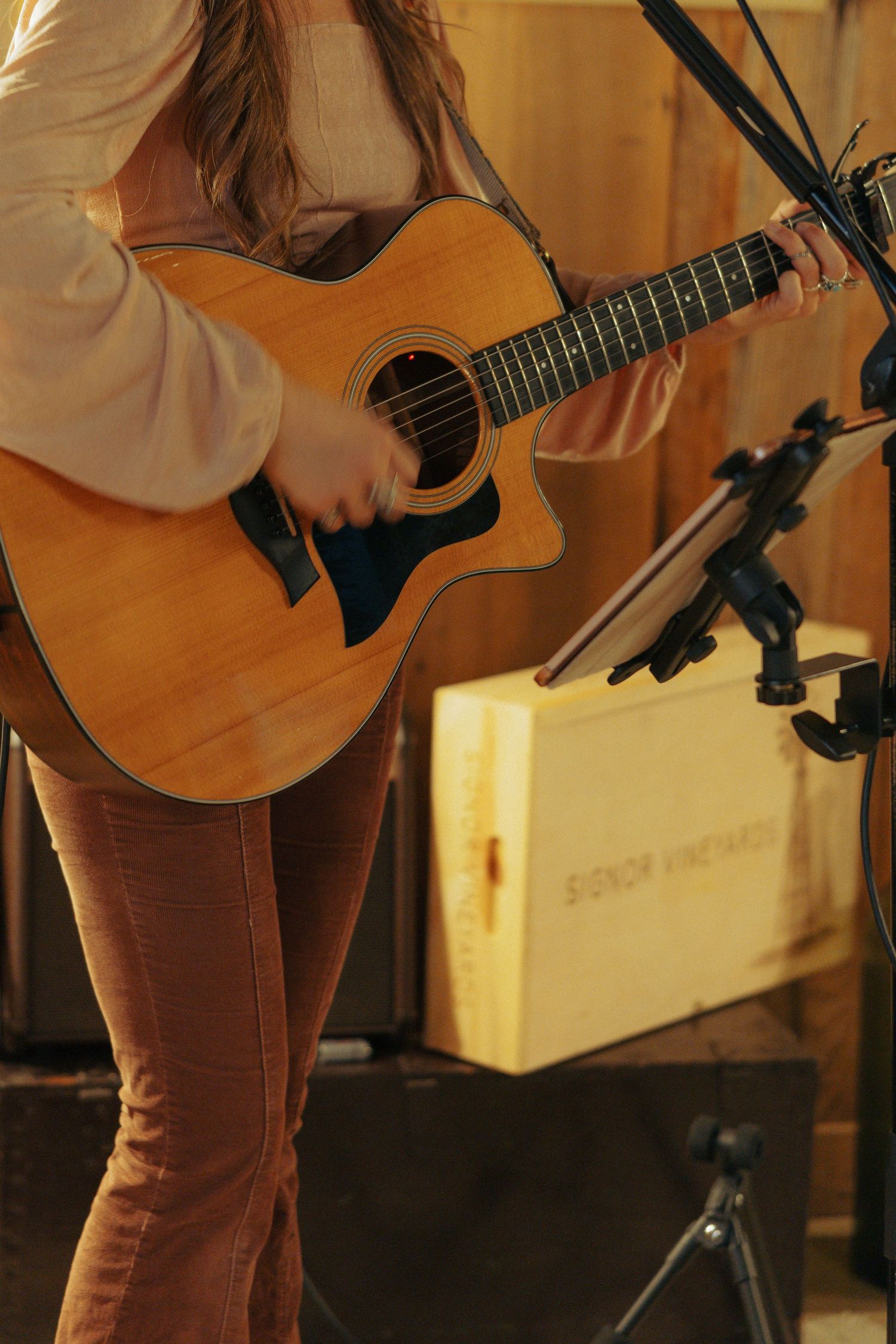 Musician performing with acoustic guitar in warm lighting.