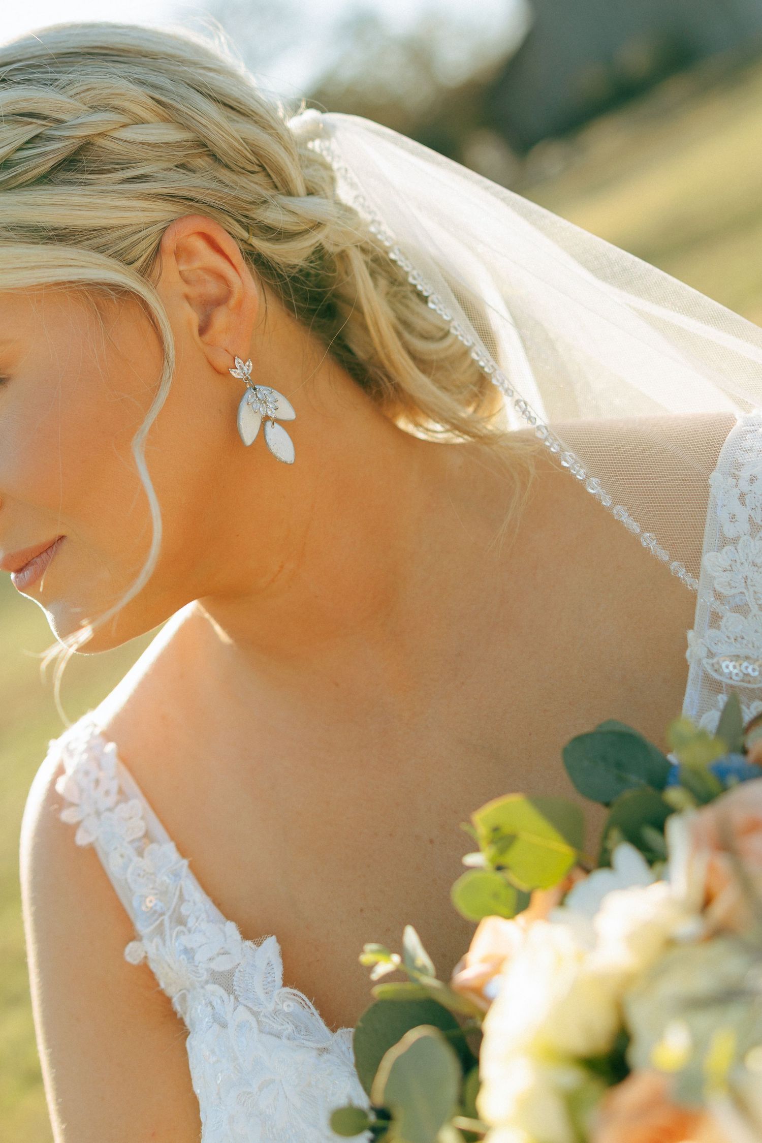 Close-up details of a delicate white lace wedding dress with floral embellishments in soft natural lighting.
