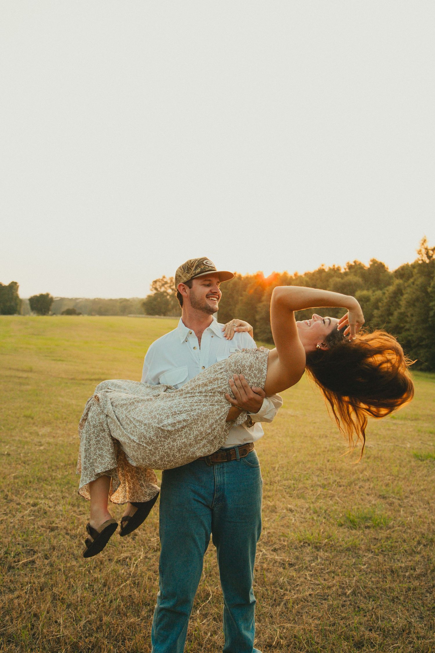 Romantic dip pose in a sunlit field during golden hour photography session.