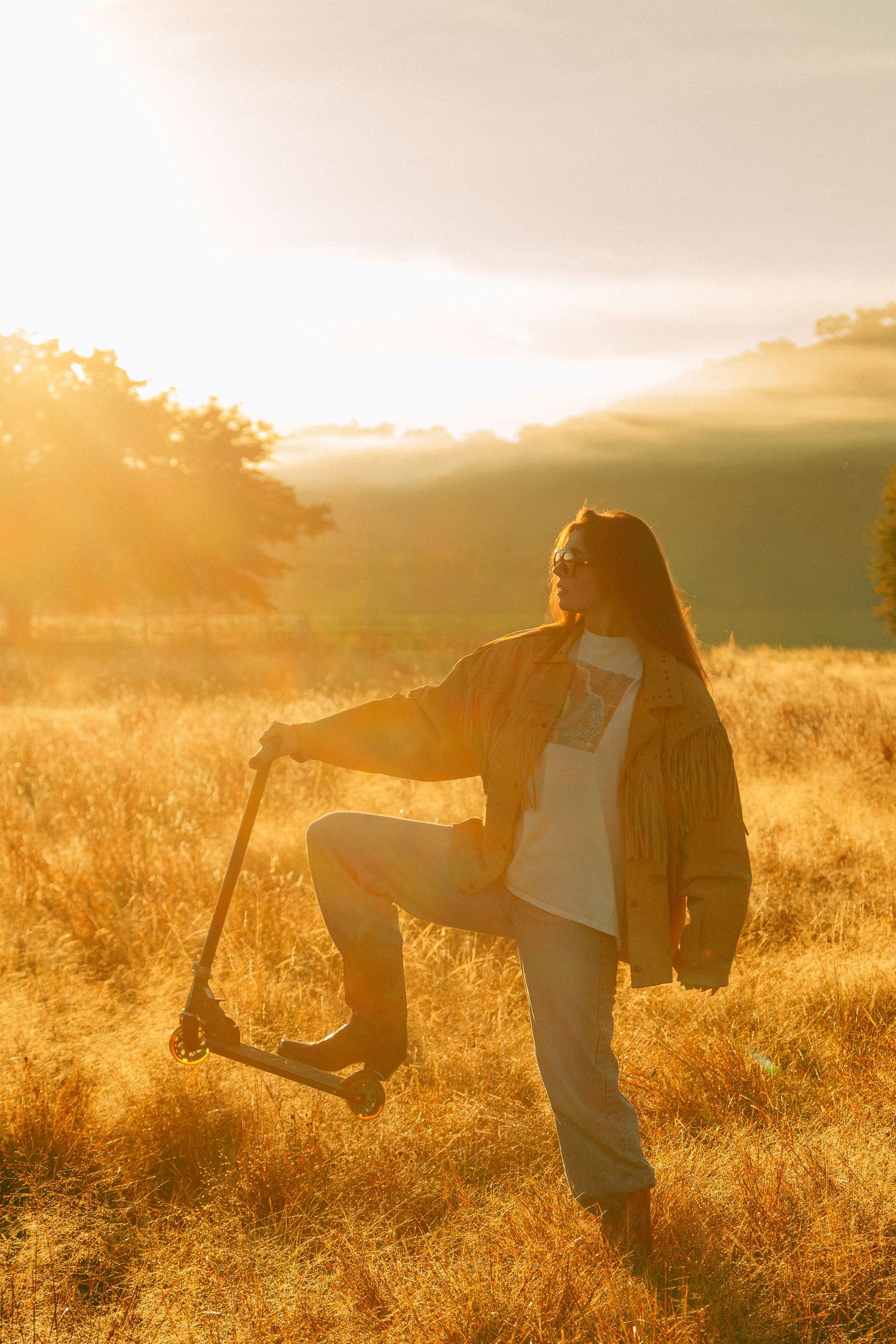 Silhouetted figure in flowing dress dances through sunlit meadow at golden hour.